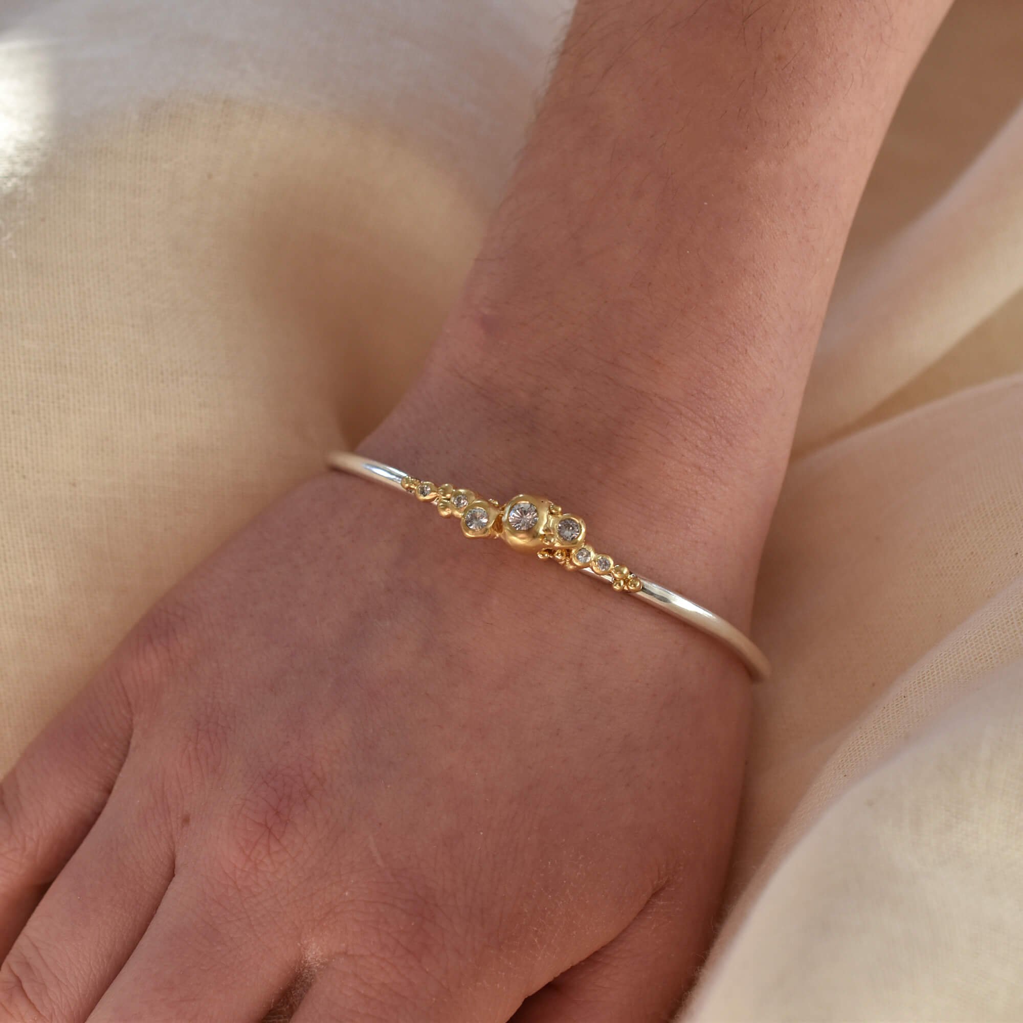 Silver and gold bubble bangle bracelet on model's arm