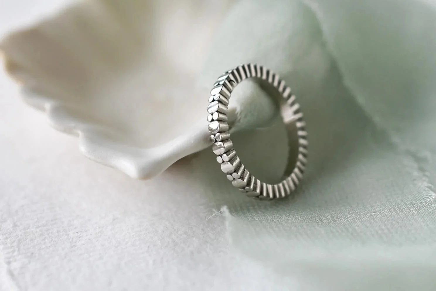 Woman's platinum wedding ring with ovals and circles with green ribbon and plate