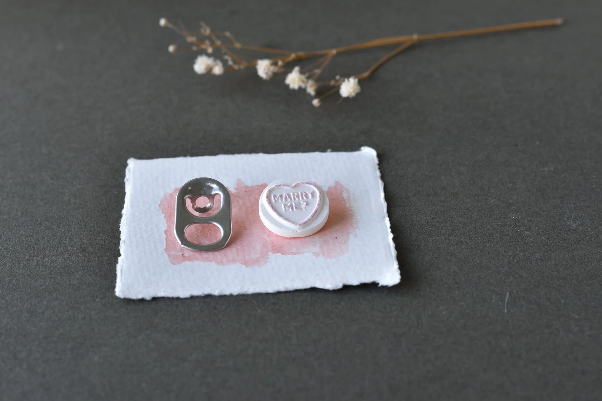 Fizzy drink ring with Marry Me heart candy and twig behind.