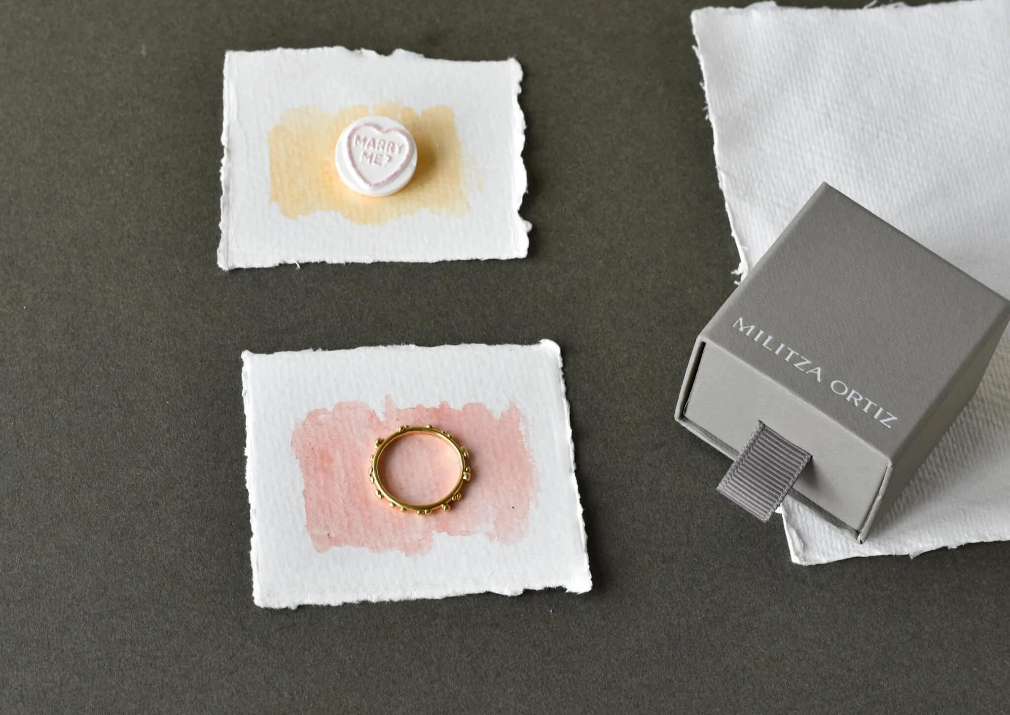 A gold placement ring shown with heart candy and Militza Ortiz jewellery box