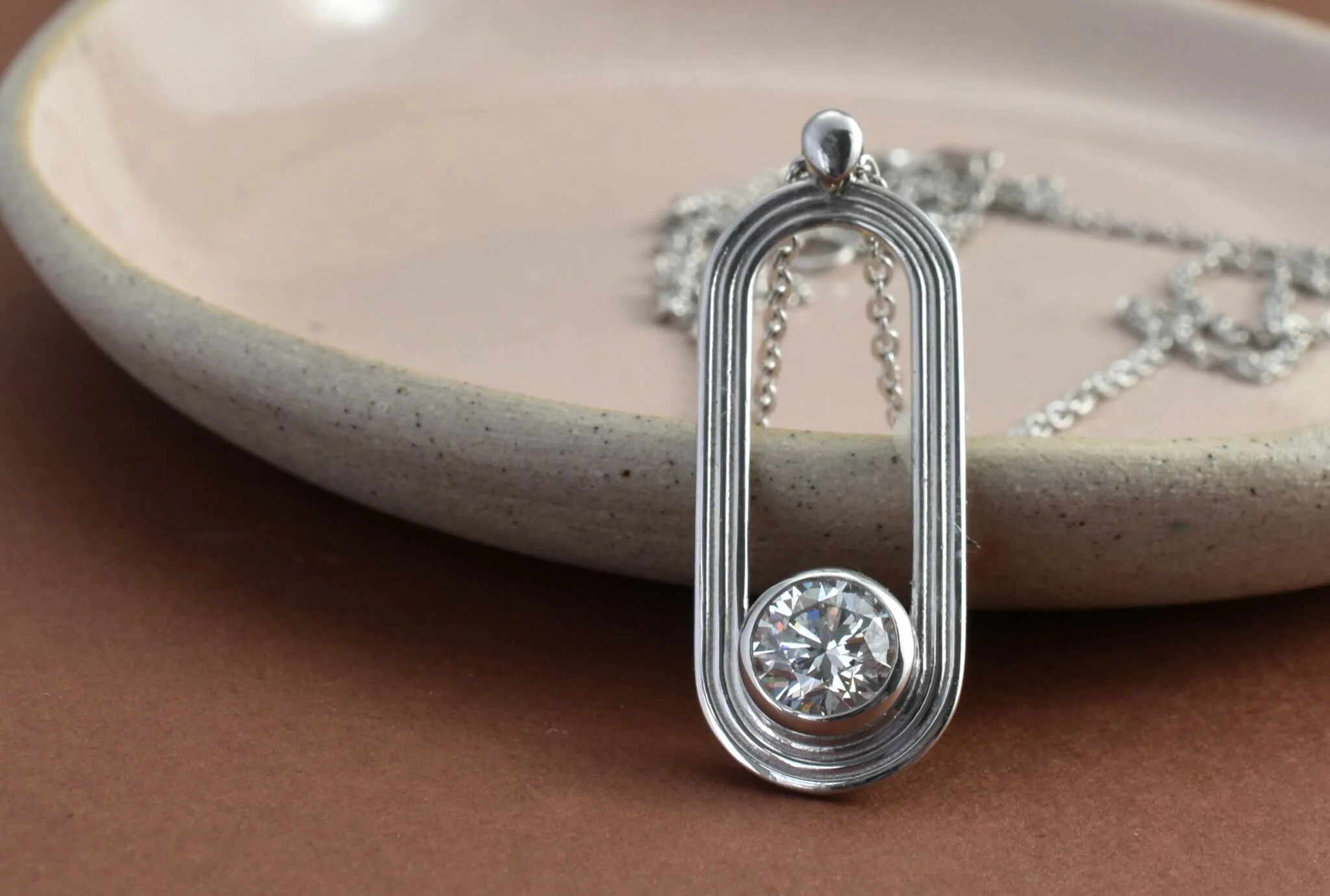 Athletics track inspired diamond pendant made in platinum shown on pink dish