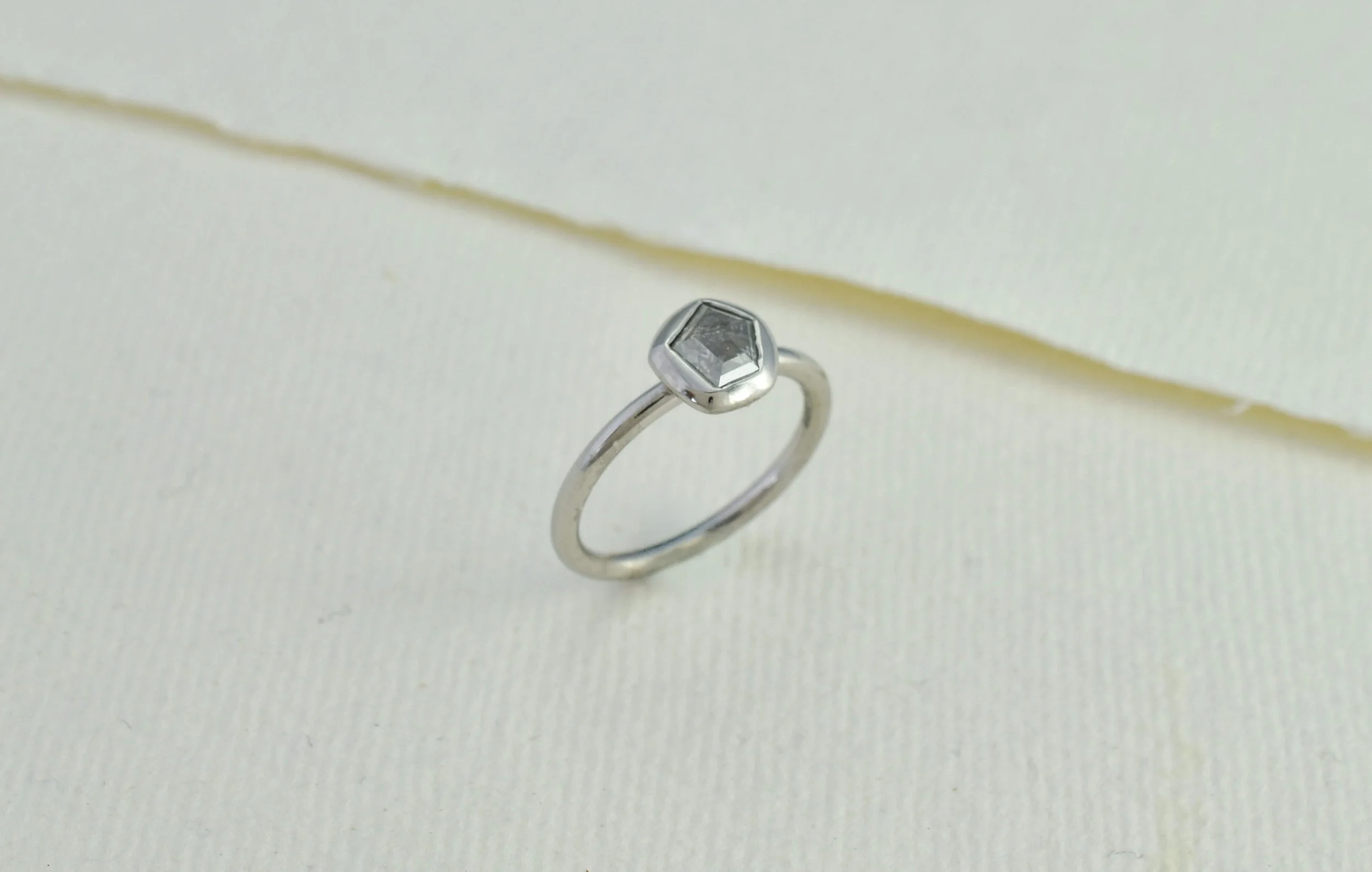 3/4 view of platinum engagement ring featuring a pentagon shaped diamond