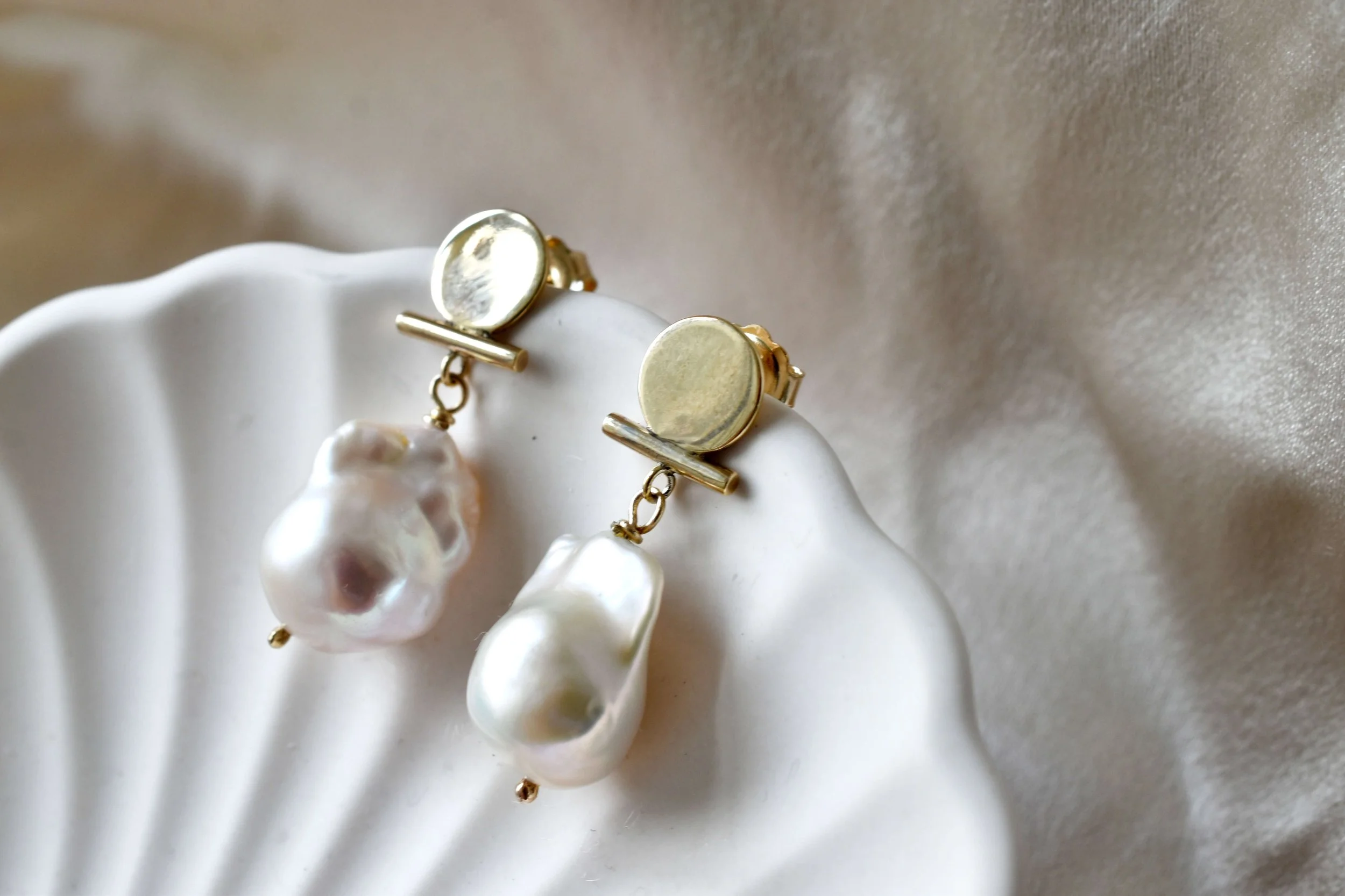 Baroque pearl earrings with gold circle on shell dish by Militza Ortiz
