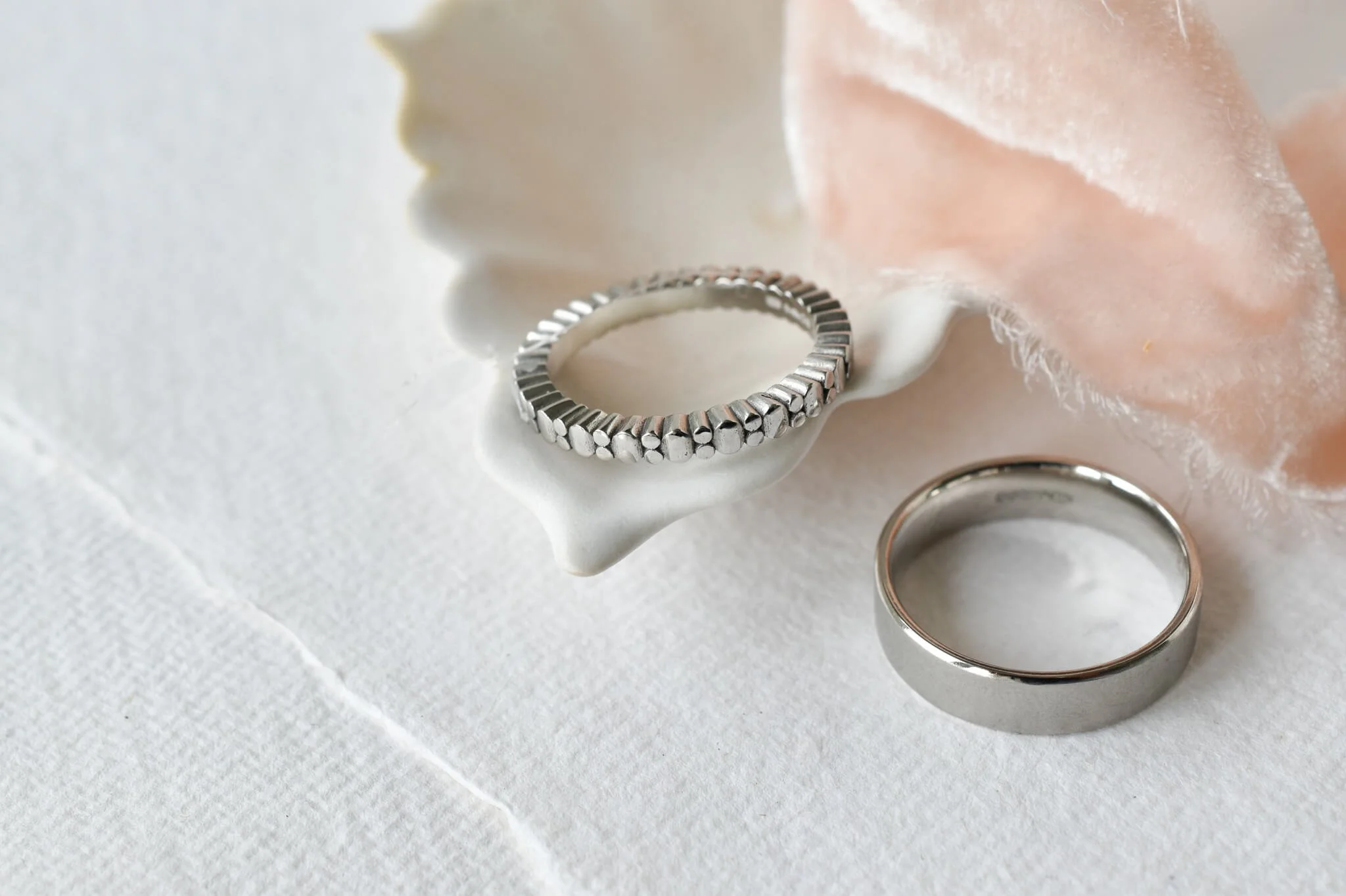 Oval and circles wedding ring with a mens platinum wedding band on plate with pink ribbon