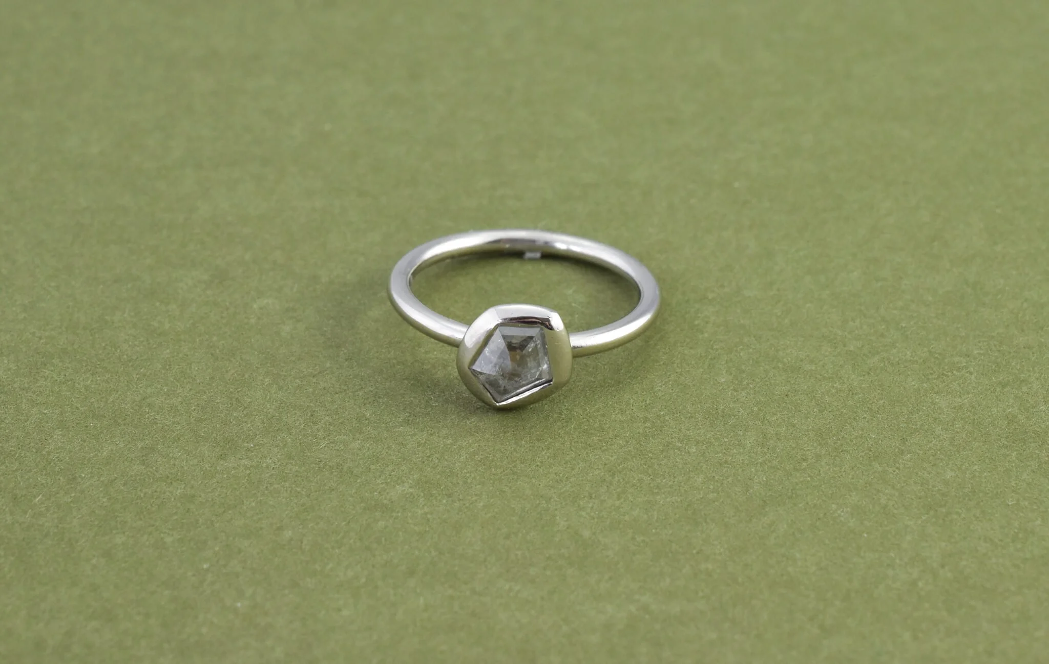 Pentagon rose shaped salt and pepper diamond ring in platinum on green card.