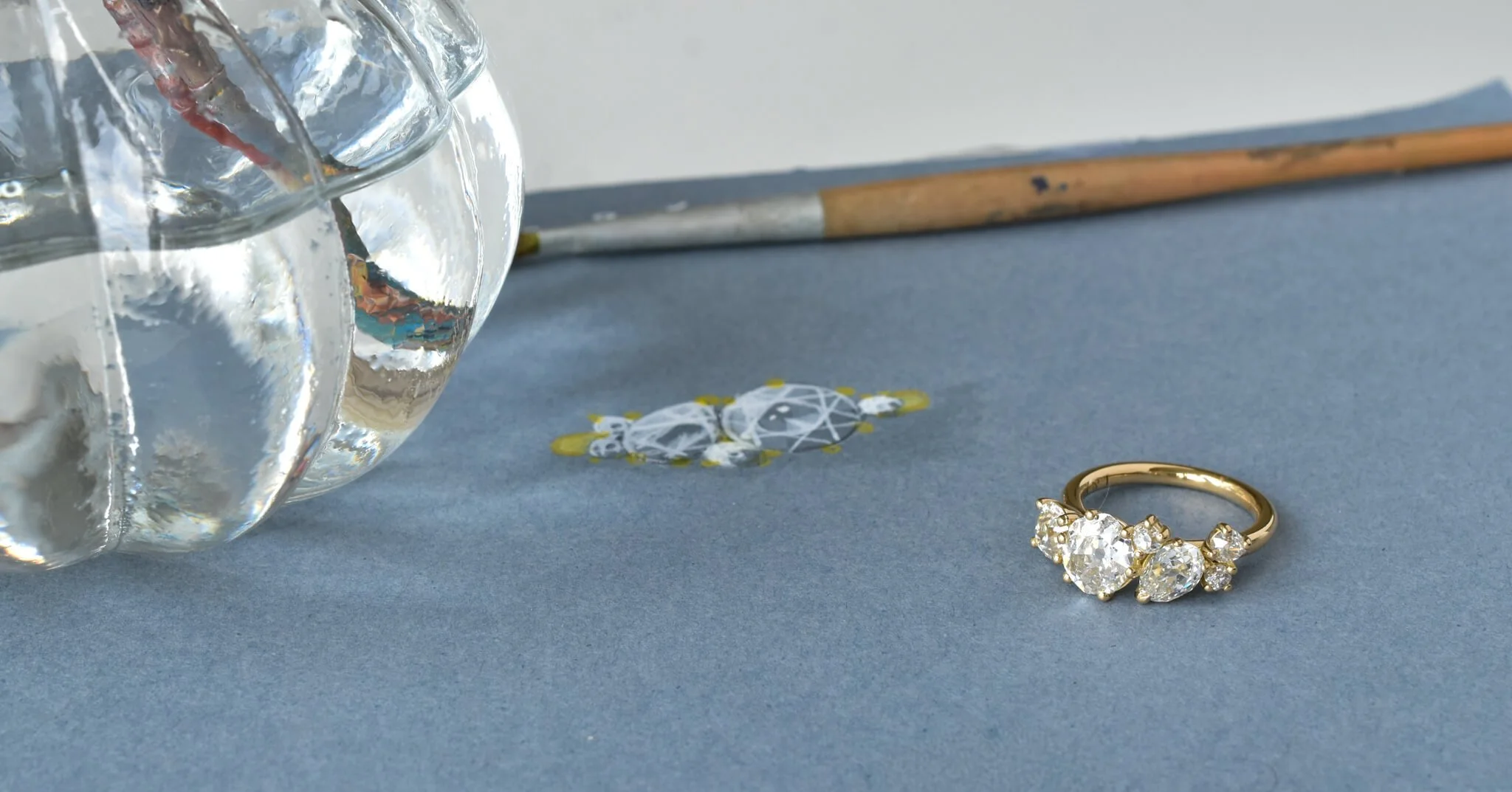 6 diamond gold ring with hand rendering paint brush and water in background