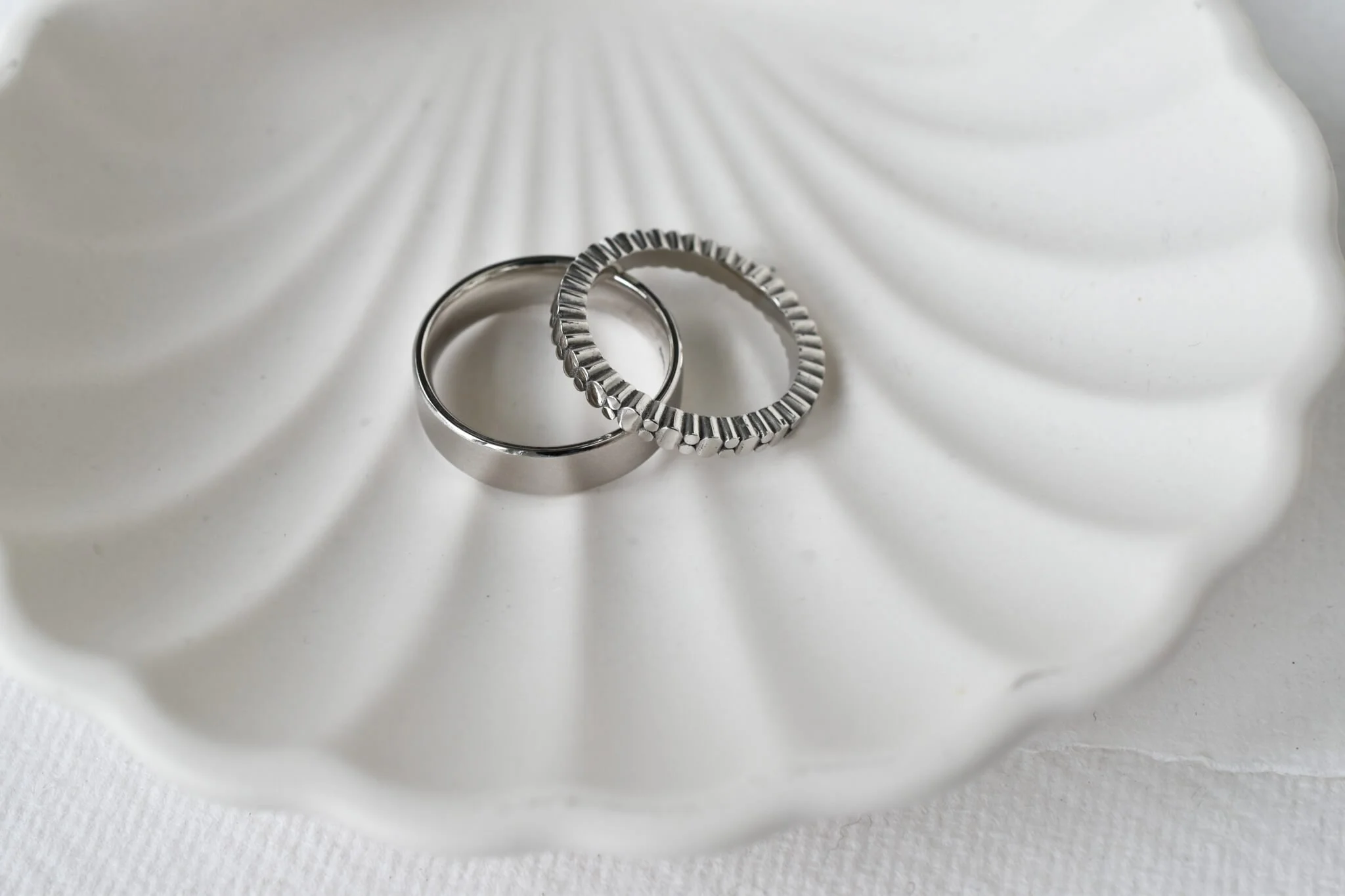 Platinum wedding bands on  shell ceramic plate
