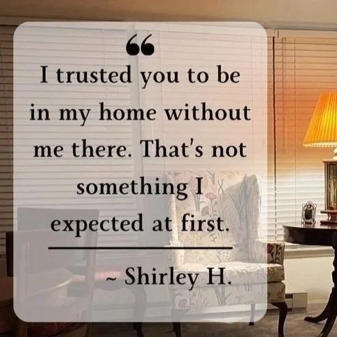 A cozy living room with two patterned armchairs, a wooden side table with a lamp, and blinds on the window. Overlaid is a quote by Shirley H. about trust and being home alone.