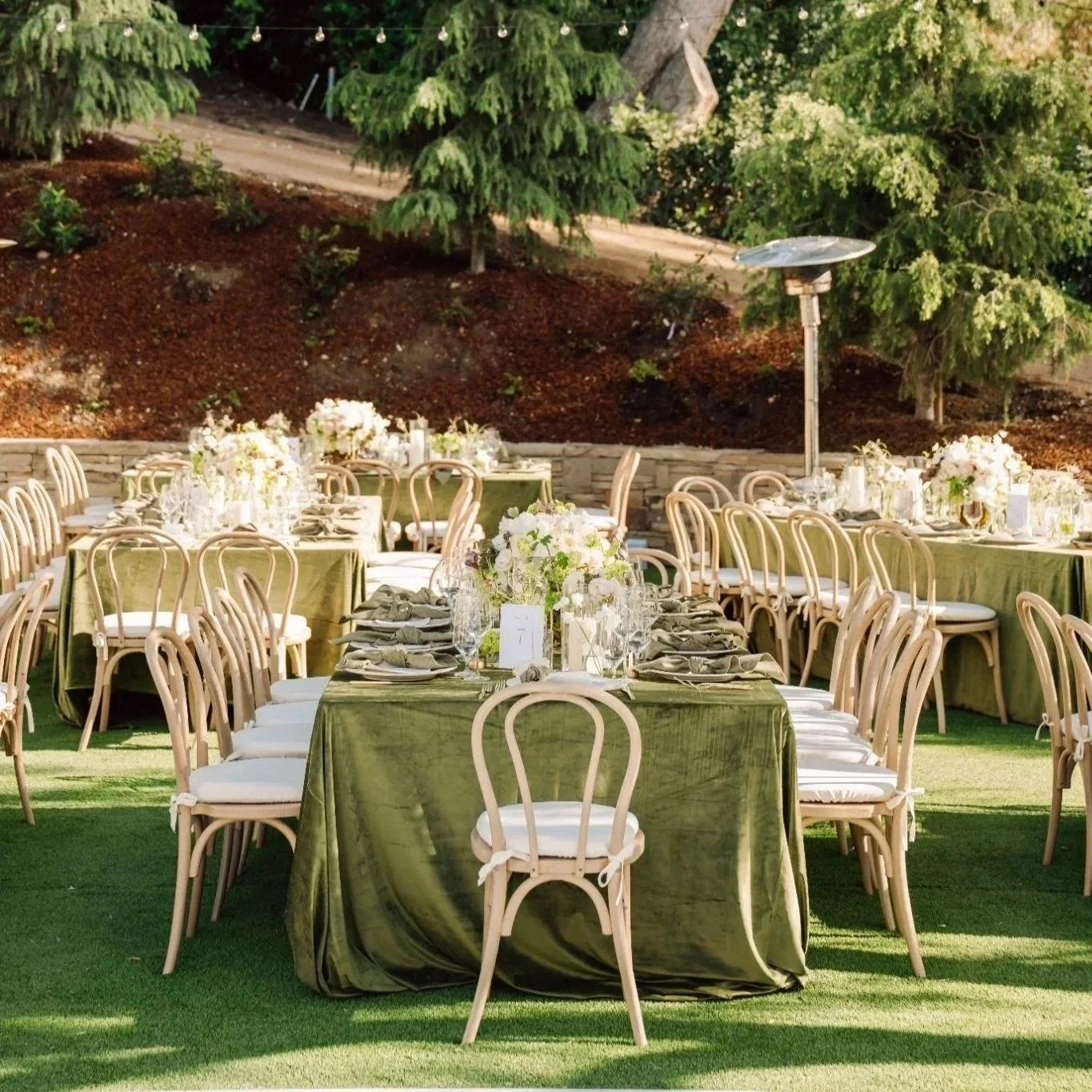Outdoor wedding reception tablescape at a private estate in Rolling Hills Estates featuring green linens, wooden chairs, and soft floral centerpieces