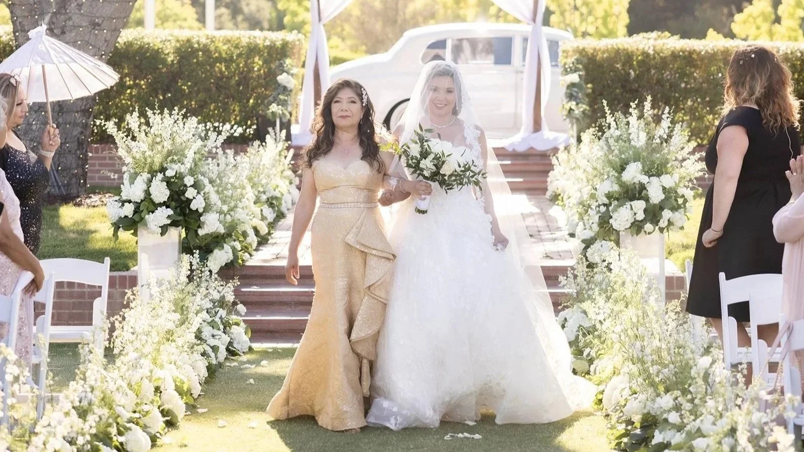 Bride walking down ceremony aisle with her mother at Sherwood Country Club with lush white floral aisle design