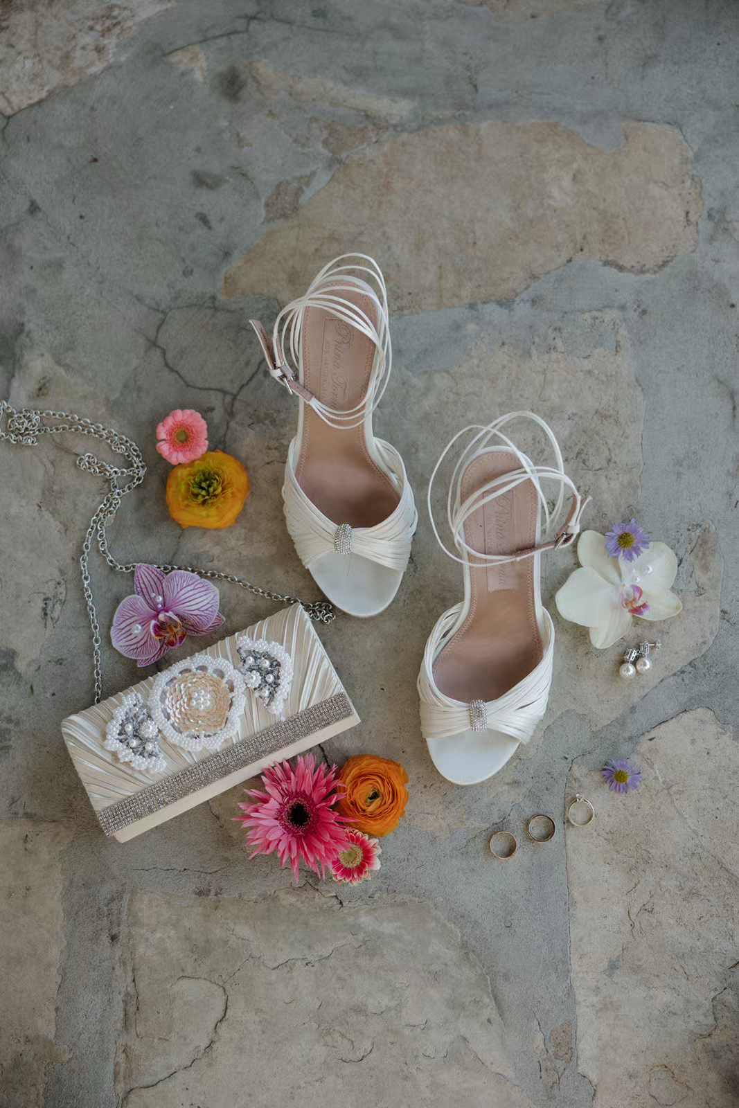 flatly with white bridal shoes, a beaded bridal clutch and florals