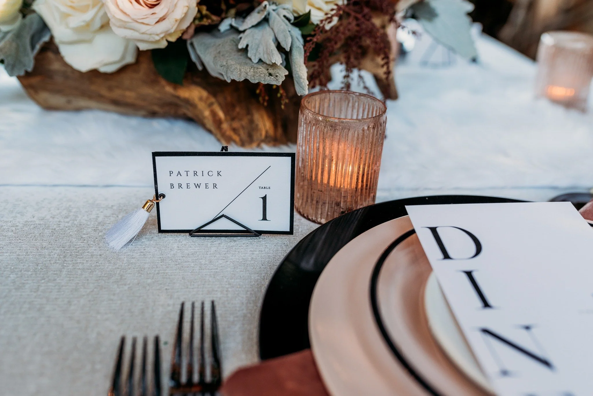 Table setting with wine glasses and place card with fringe tassel at South Coast Winery fall wedding editorial in Temecula