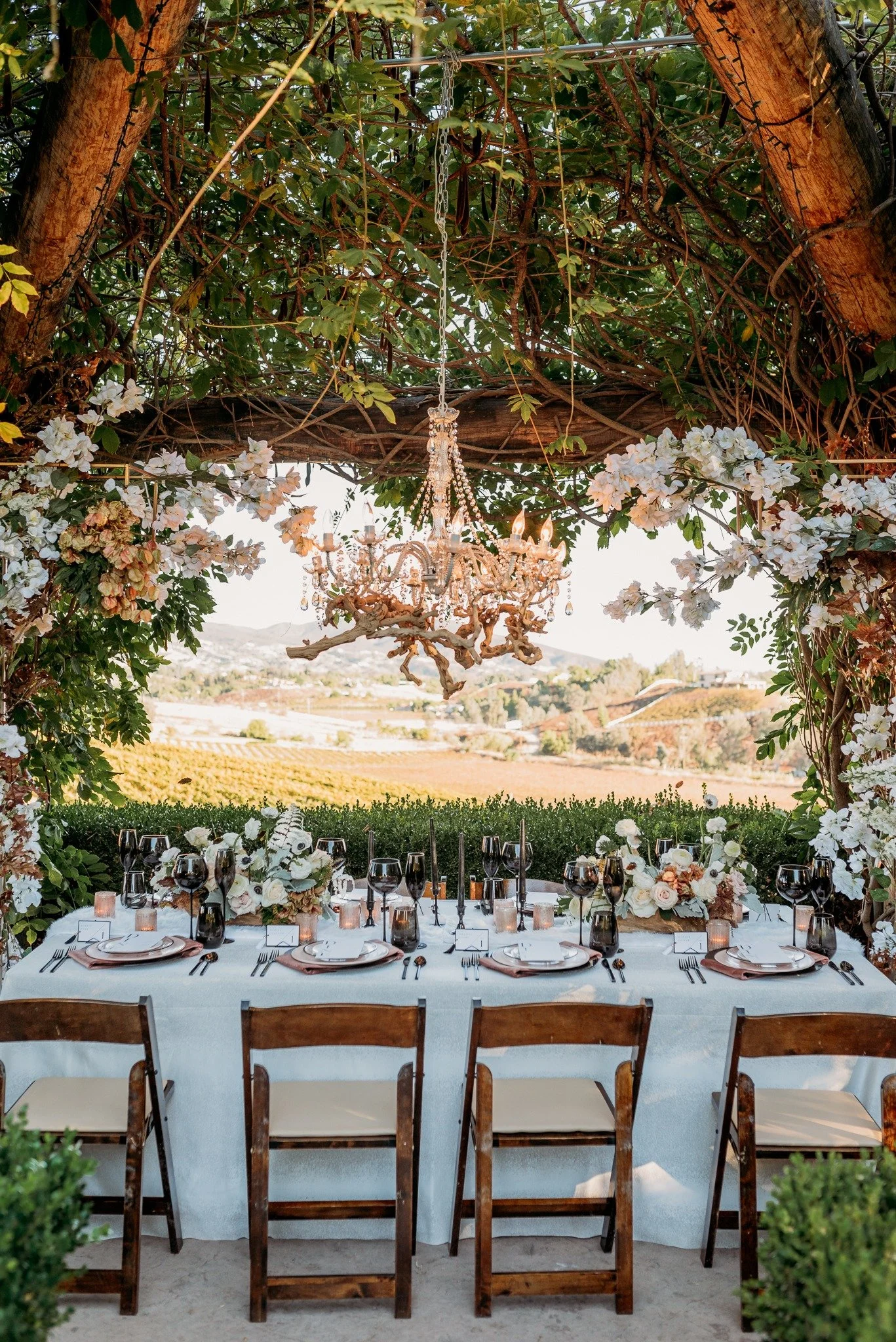 Outdoor vineyard wedding reception at South Coast Winery with floral installation and long tables overlooking Temecula vineyards