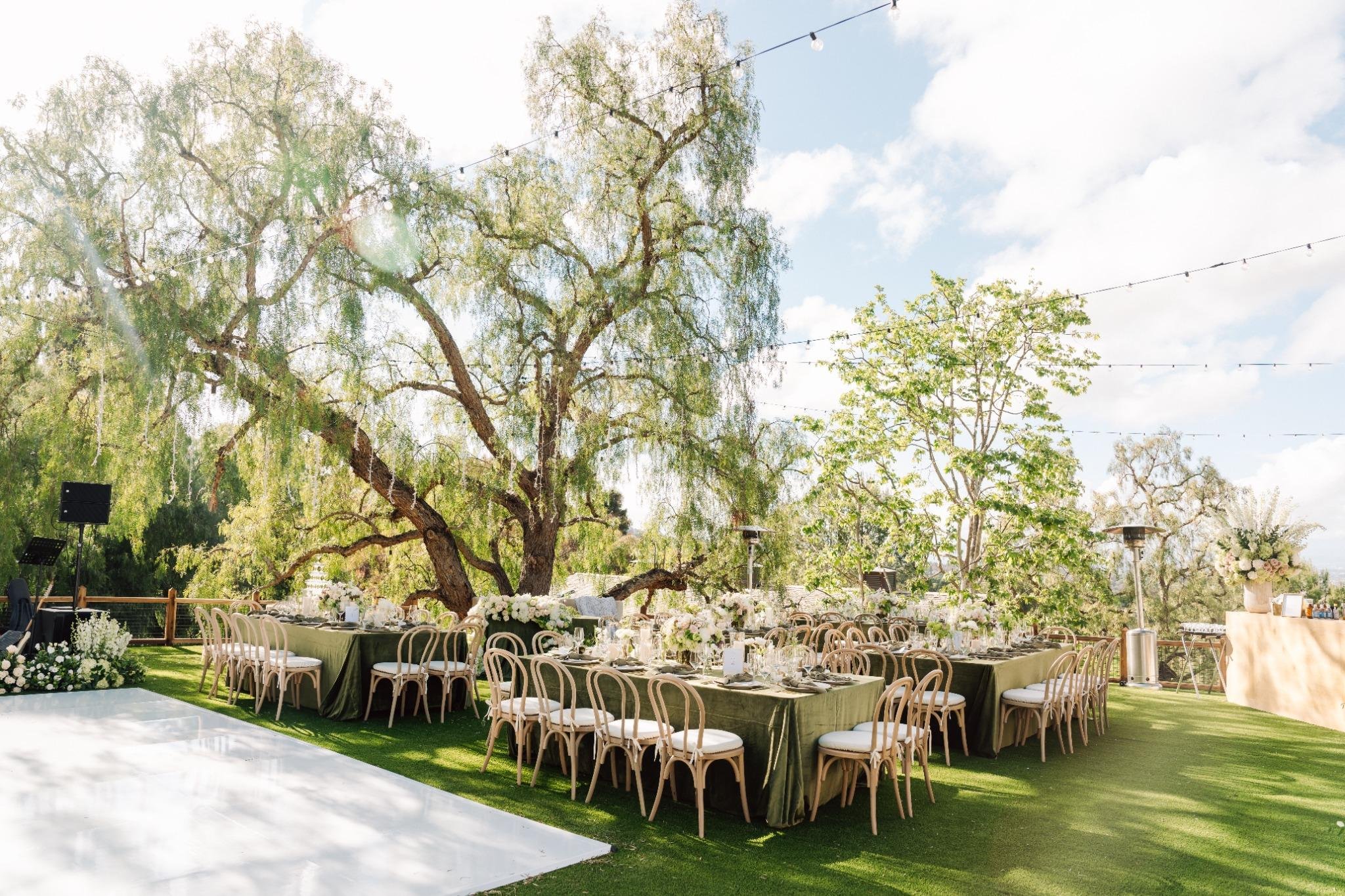 Outdoor estate wedding reception in Rolling Hills Estates with long tables, string lights, and lush greenery setting