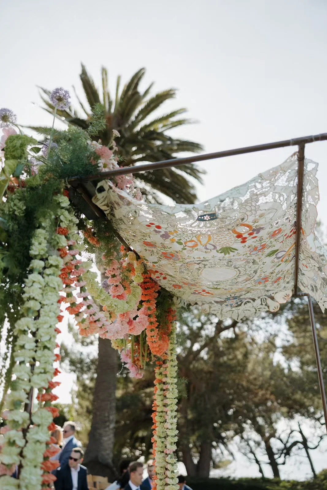jewish huppah at ceremony with bold colored flowers and a lace fabric