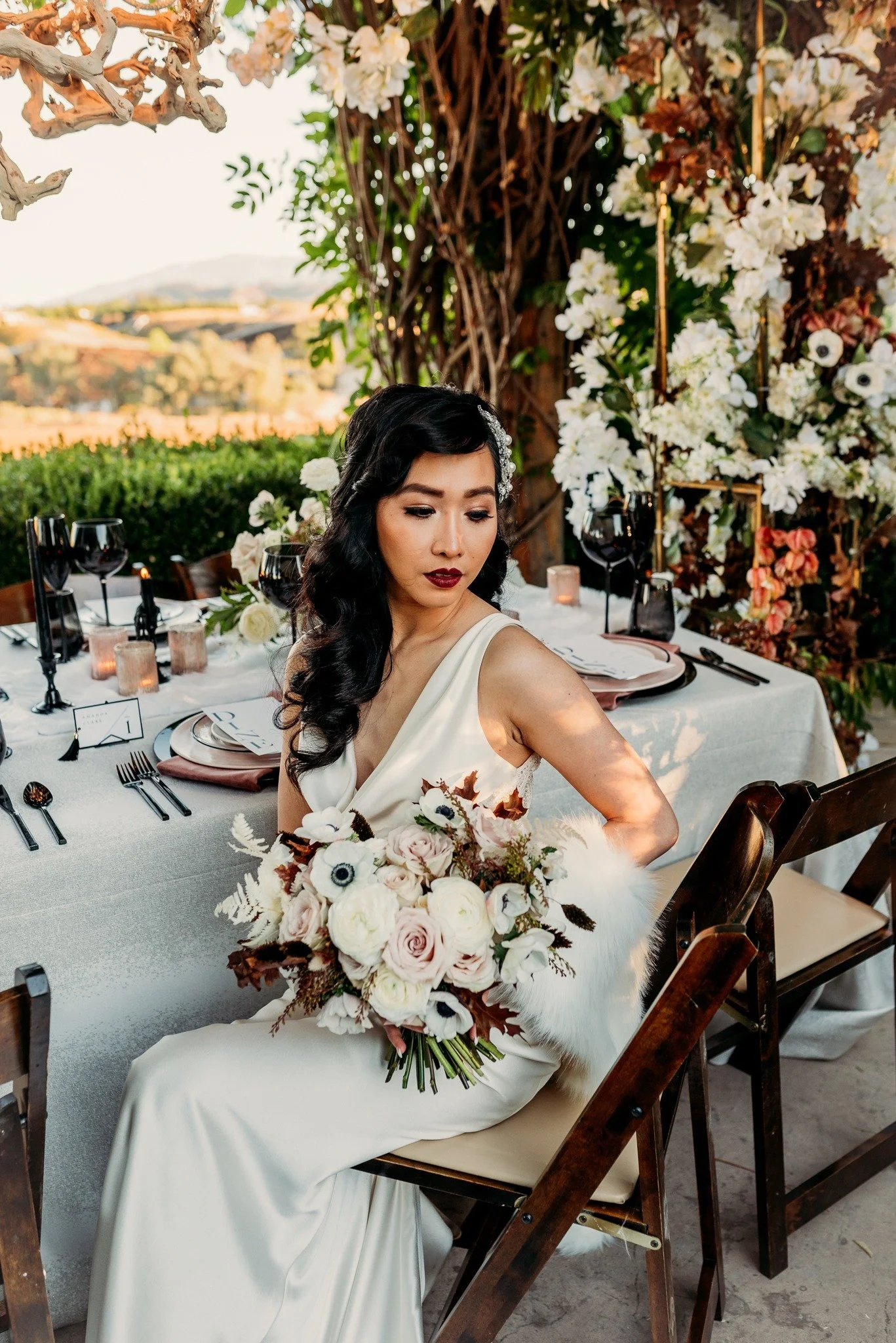 Bride seated at reception table during South Coast Winery fall wedding editorial with lush florals and vineyard backdrop