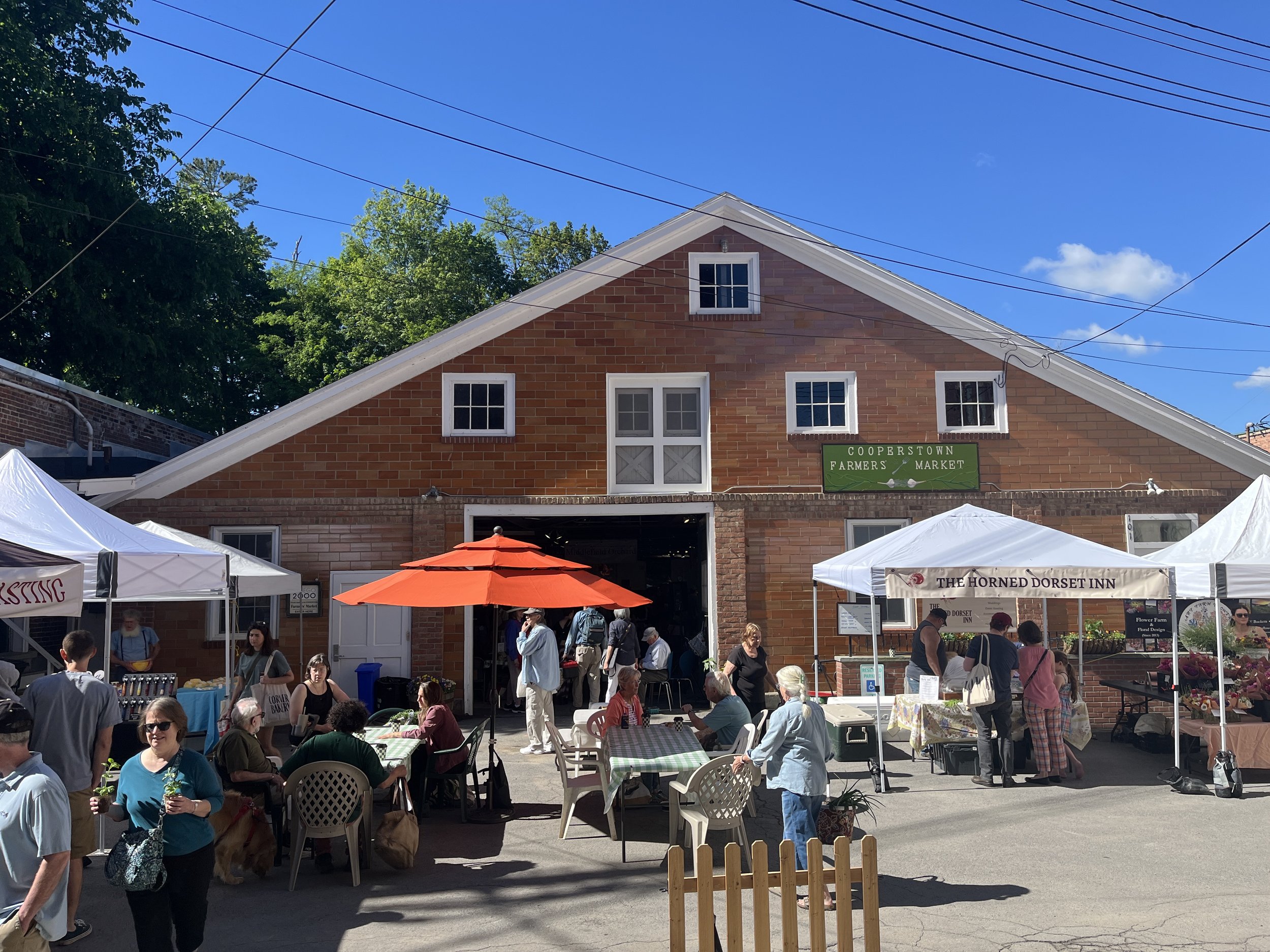 The Cooperstown Farmers' Market with vendor tents outside and seating for customers.
