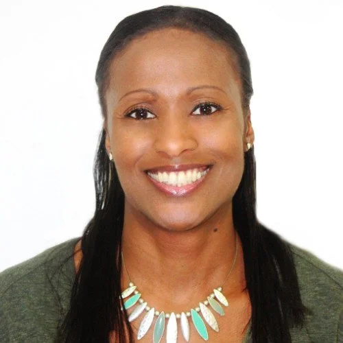 Smiling woman with long dark hair, wearing a green top and a turquoise and white necklace.
