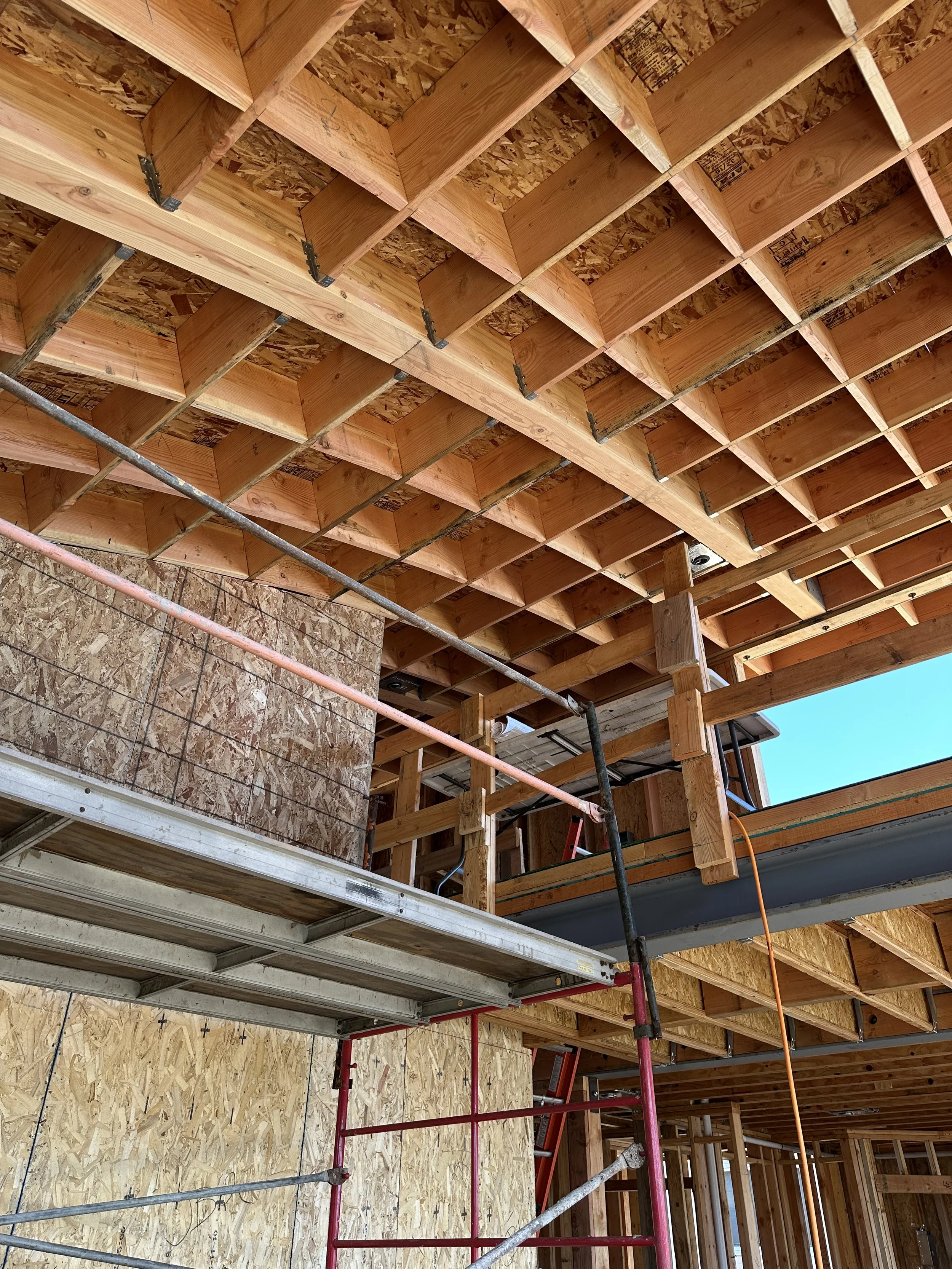 Construction site with wooden framing for a building, scaffolding, and interior wall sheathing.
