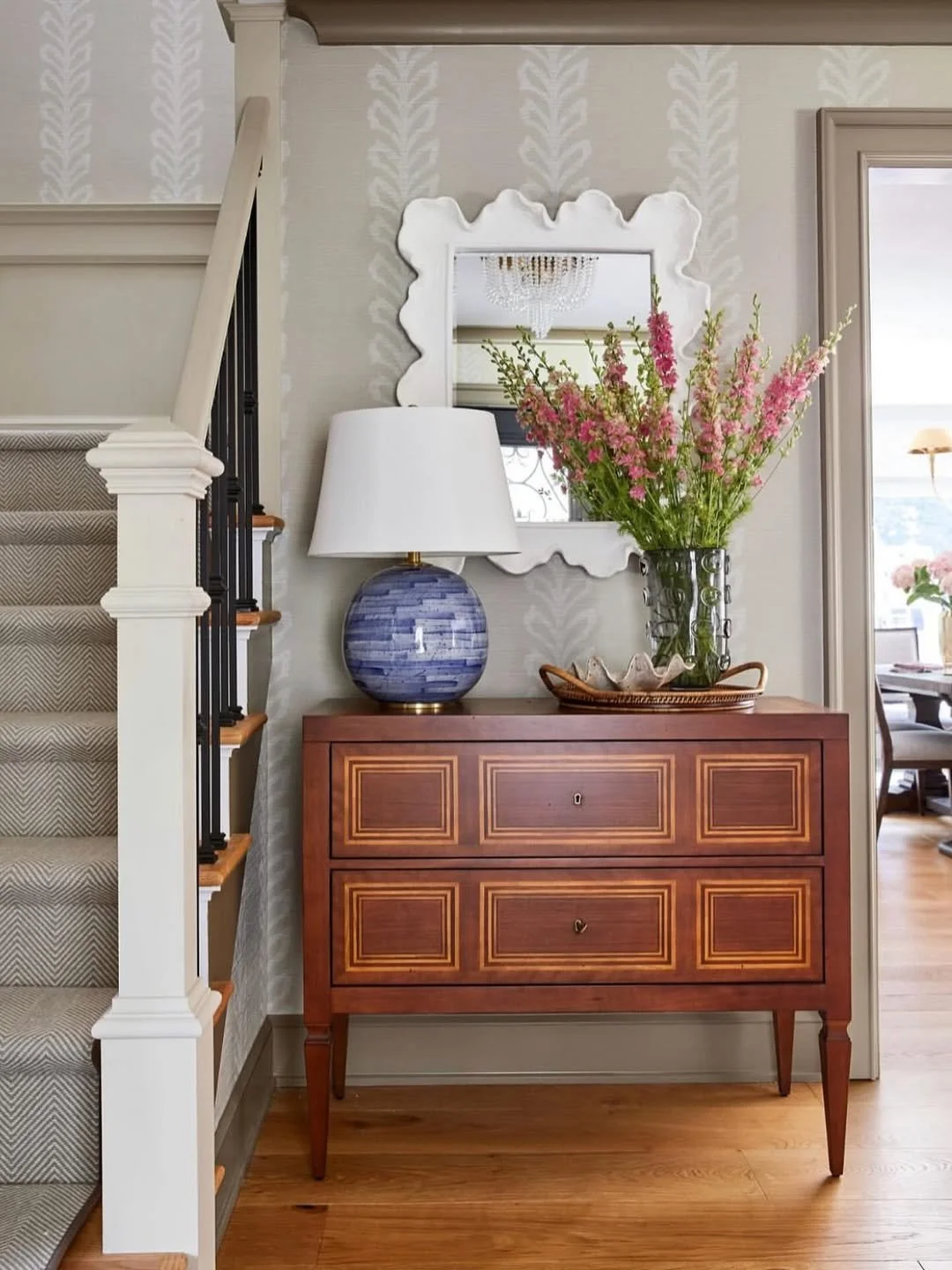 In this inviting entry by @kristinaphillipsinteriordesign, the Milan Commode (MH561F01) from @modernhistoryfurniture strikes the perfect balance of polish and personality. Crafted in rich fruitwood with delicate inlay, it brings timeless elegance to