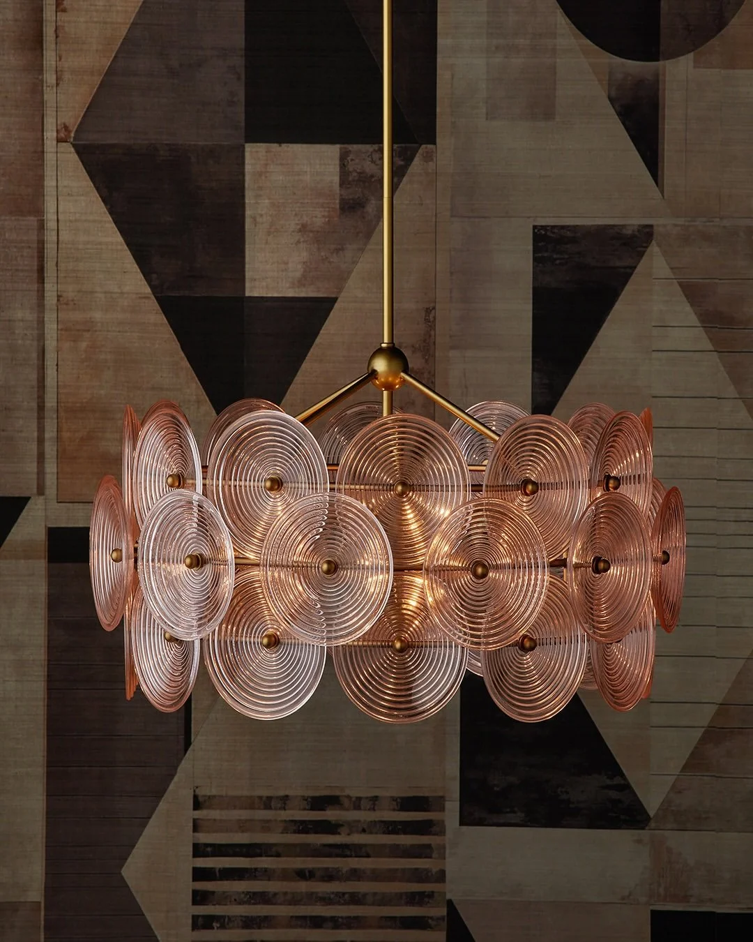 A soft swirl of color and light.

New for Spring 2026, the Whirlwind Medium Pink Chandelier from @curreyco is composed of ribbed, concave glass discs that catch and scatter light with gentle movement. Set against a warm brass frame, the blush-toned g