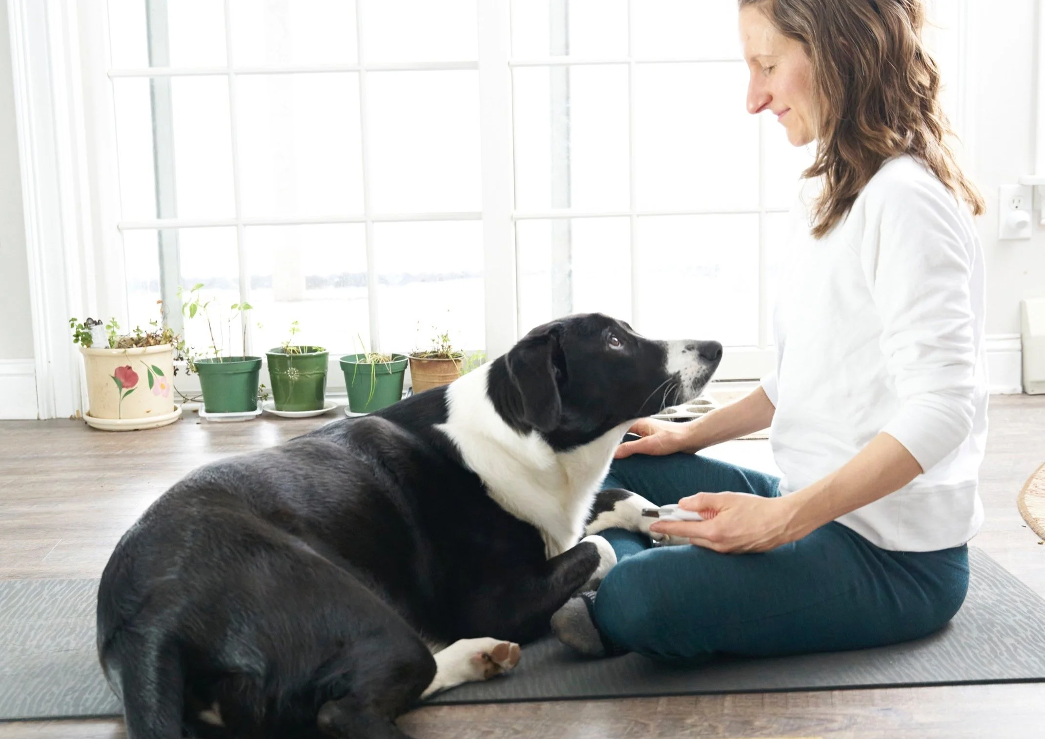 Sharon and Muggins sit on a yoga mat facing and gazing into each others' eyes.