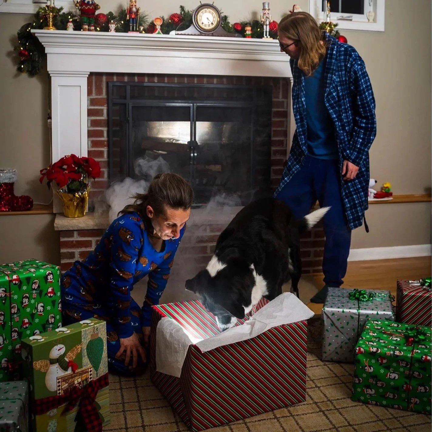 Image shows Sharon and Muggins peering excitedly into a brightly lit box among red and green wrapped gifts.