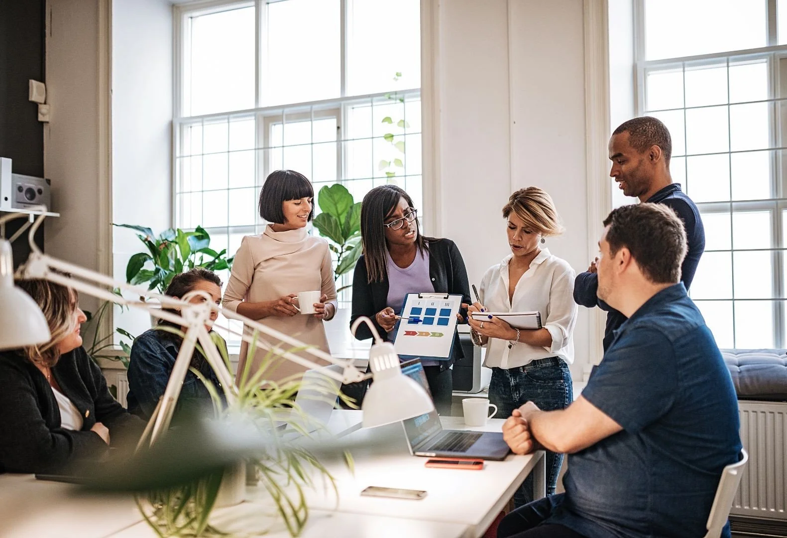 A diverse group of business professionals collaborating during a leadership and teamwork session, illustrating the impact of an inspirational keynote speaker on workplace performance.
