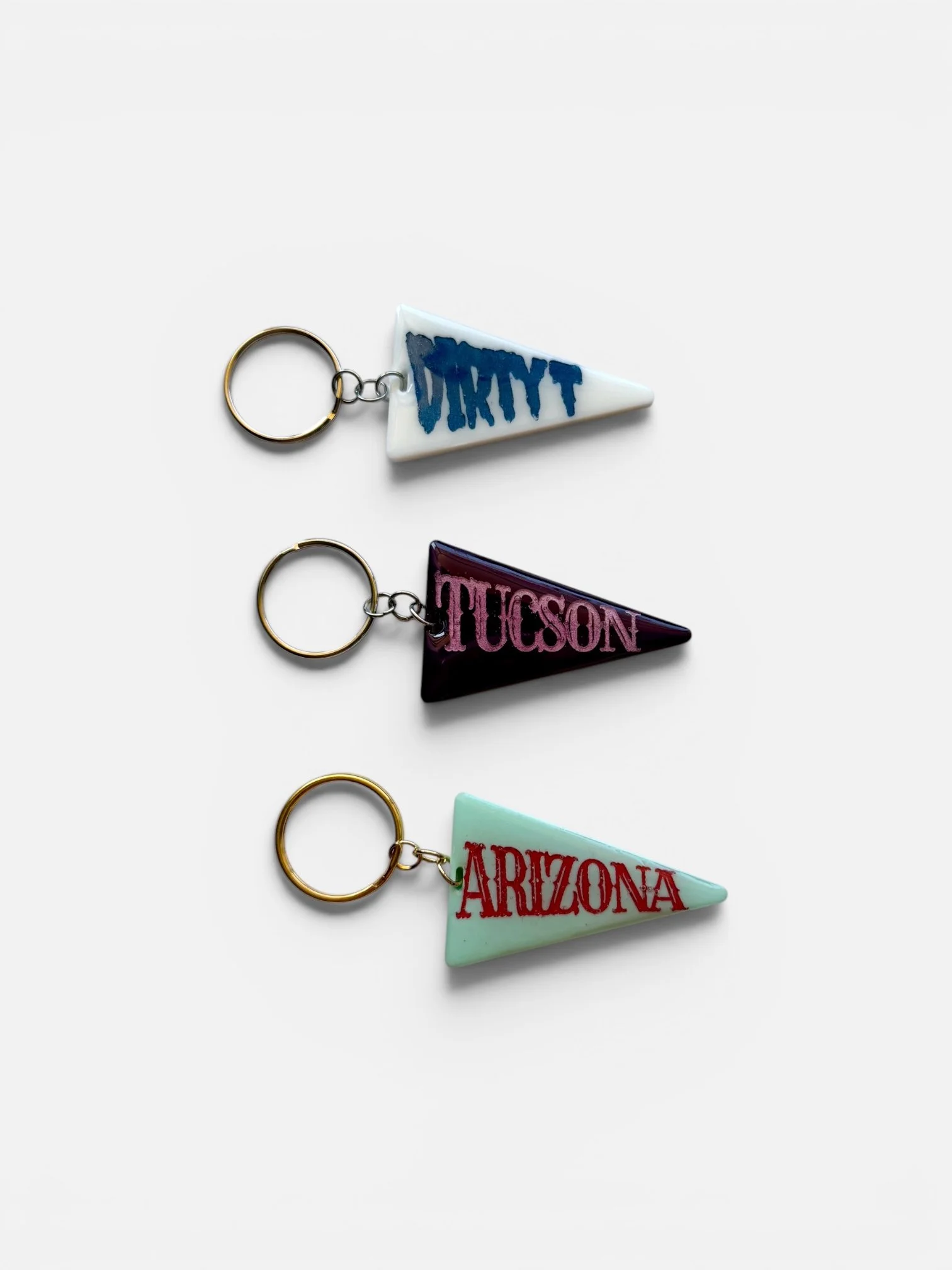 Colorful handmade pennant keychains featuring Arizona, Tucson, and Dirty T designs with vintage souvenir style.