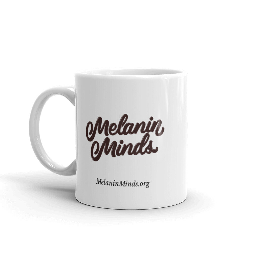 White 11 oz mug with handle on the left, featuring dark brown Melanin Minds logo & MelaninMinds.org