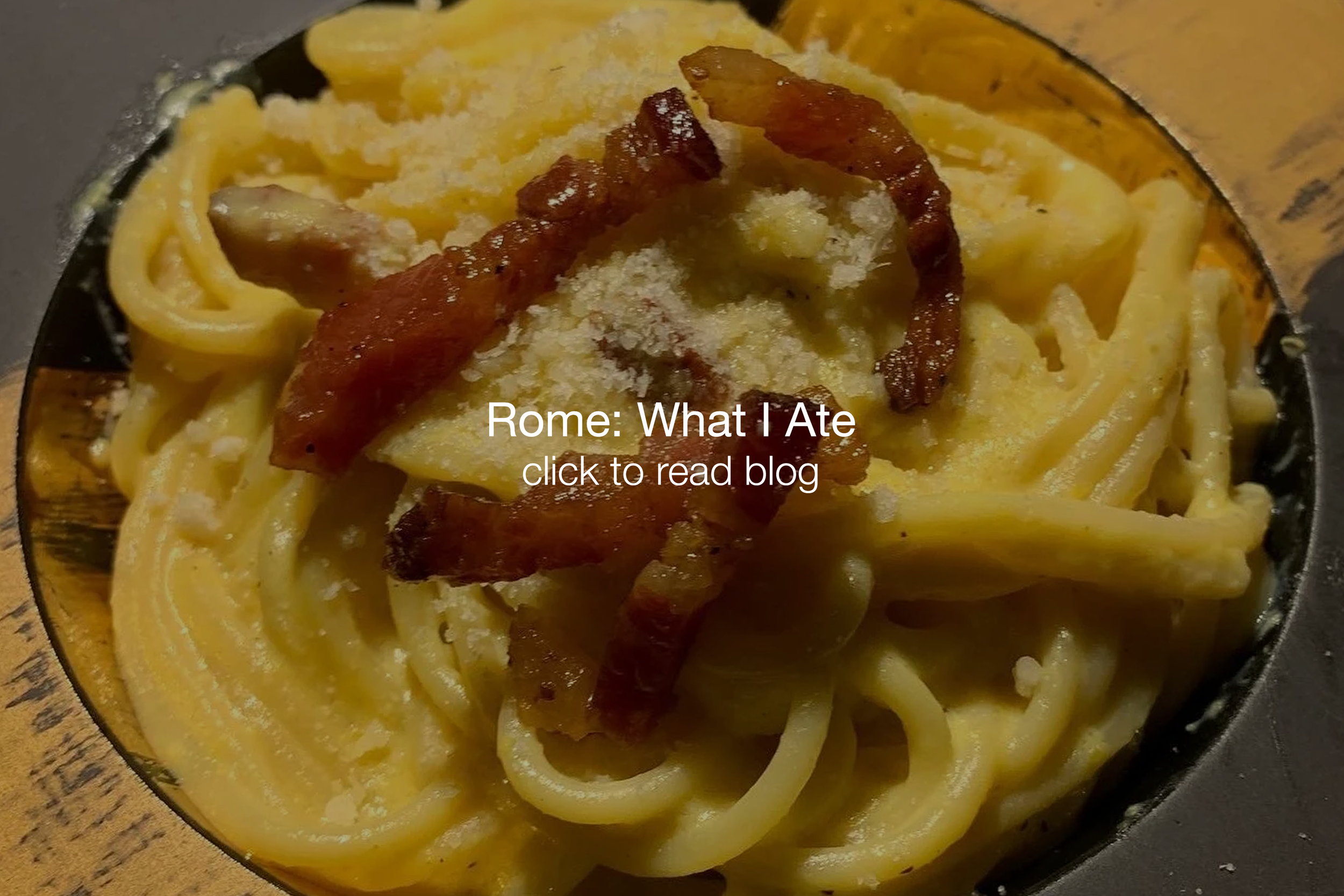 Close-up of a bowl of spaghetti with grated cheese, bacon strips, and grated parmesan cheese on top.