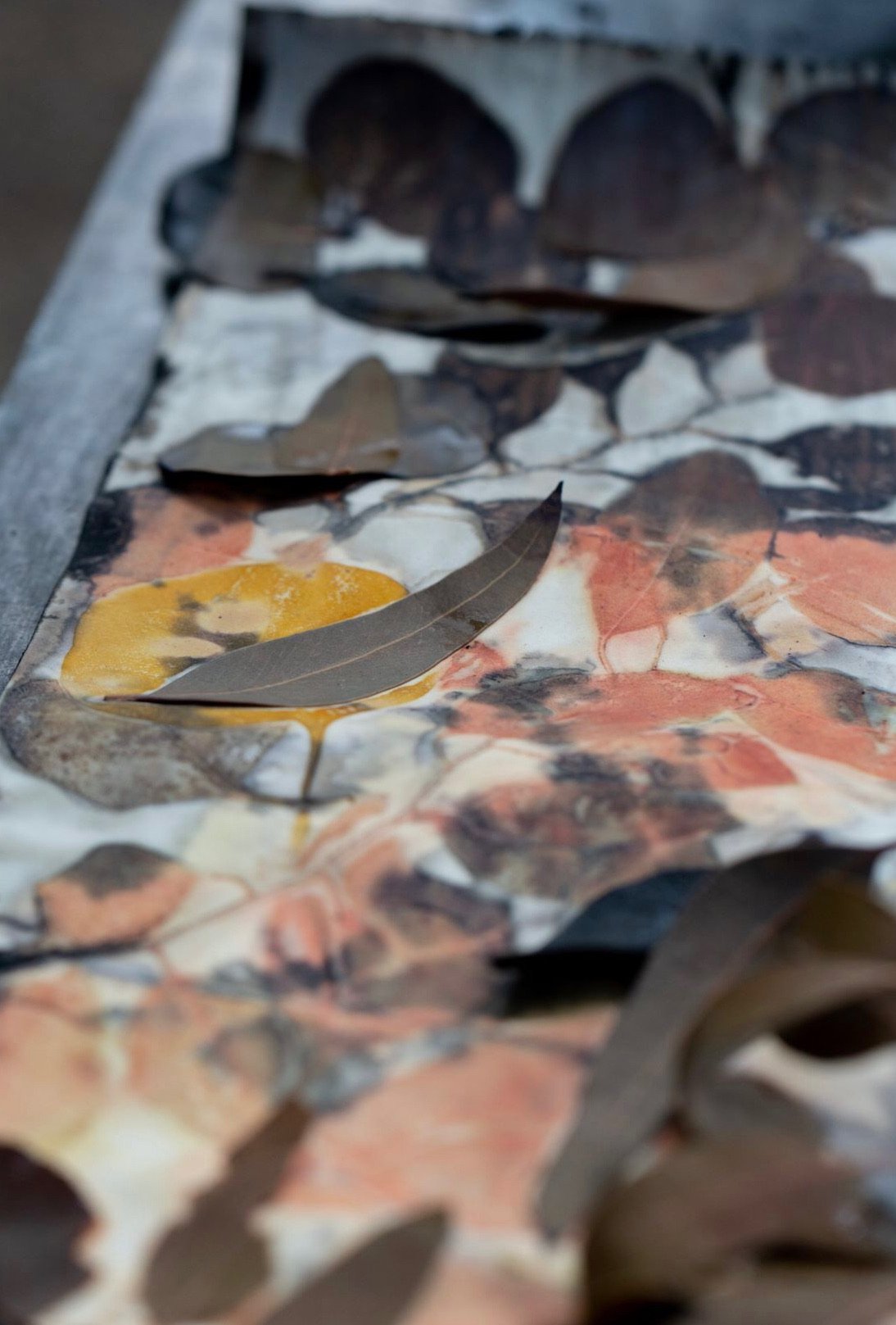 Close-up of autumn leaves scattered on a multicolored stone surface.