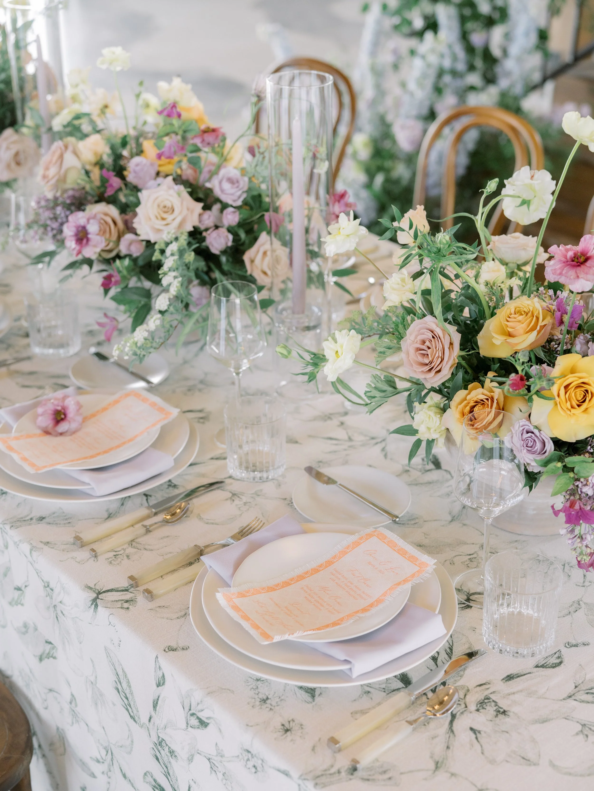 Elegant table setting with floral centerpiece, white plates, silverware, and glasses at a decorated event.