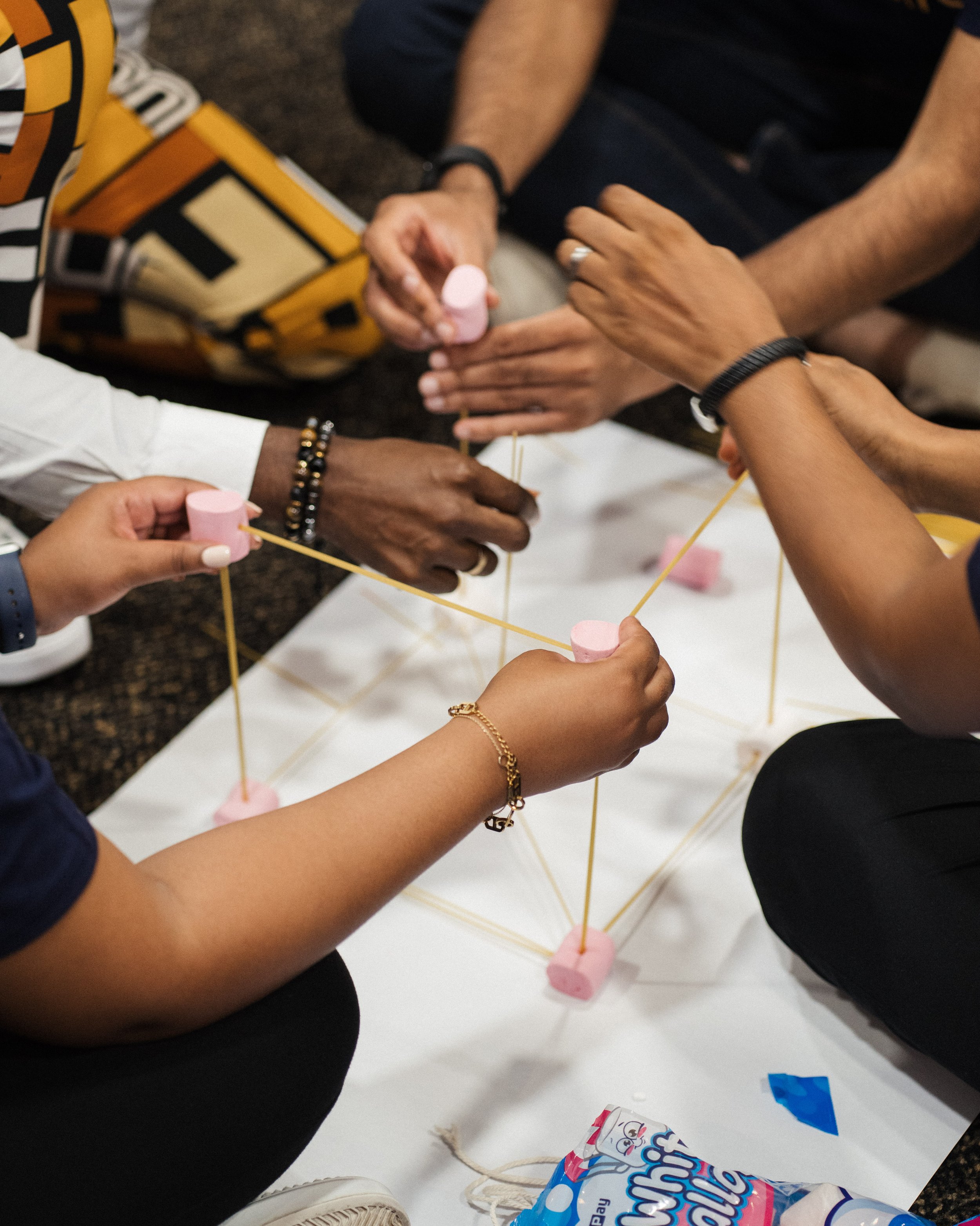 Person presenting in front of a whiteboard with notes, wearing glasses and a green shirt. The whiteboard contains handwritten text about boundaries and cultural initiatives. Background features wooden panels with paper sheets and drawings.
