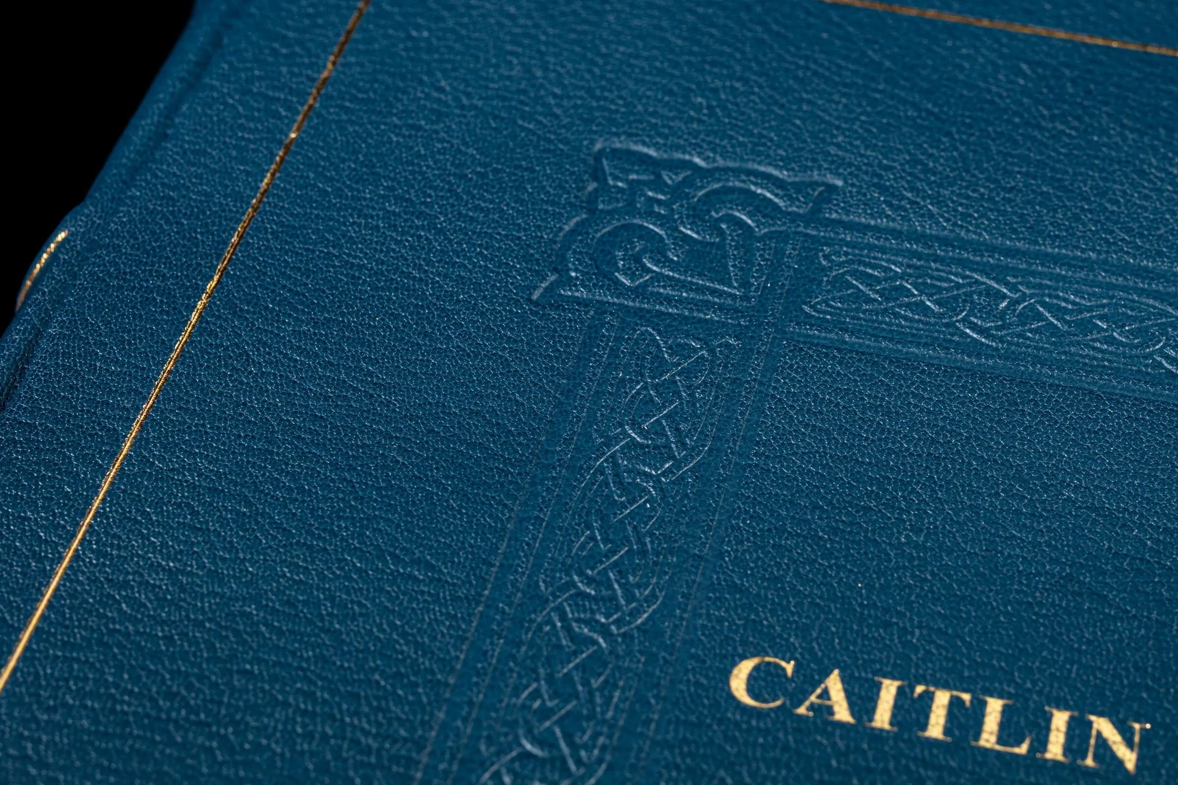 Close-up of a navy blue leather-bound book with gold text and embossed patterns on the cover.