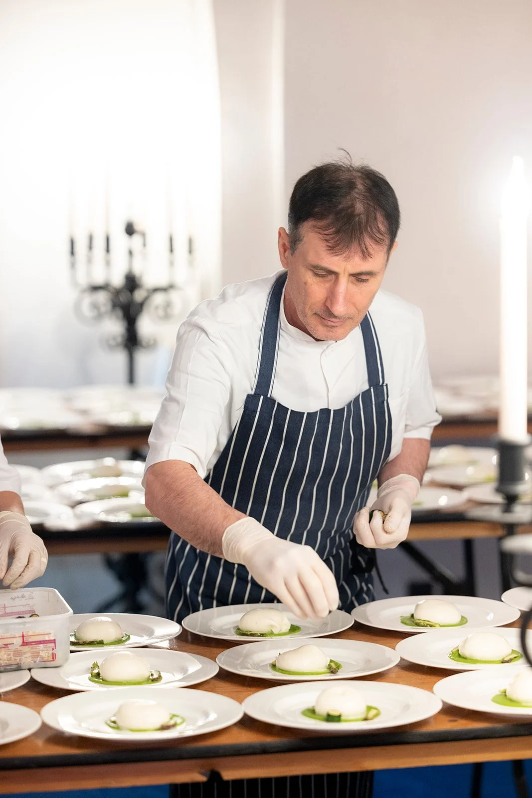 Chef garnishing plates with food in a professional kitchen.