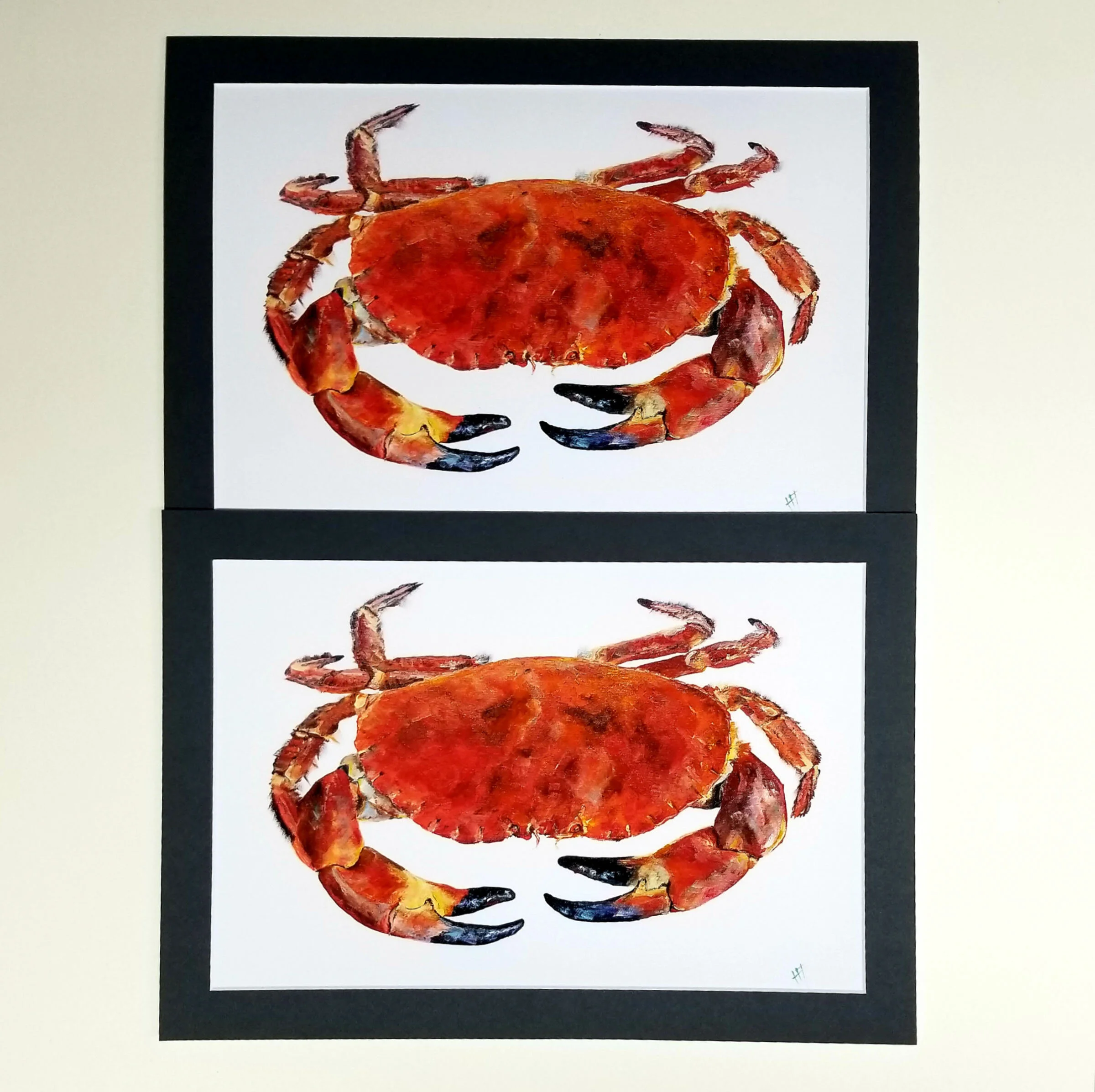 Two framed illustrations of red crabs on a white background, placed on a black background.