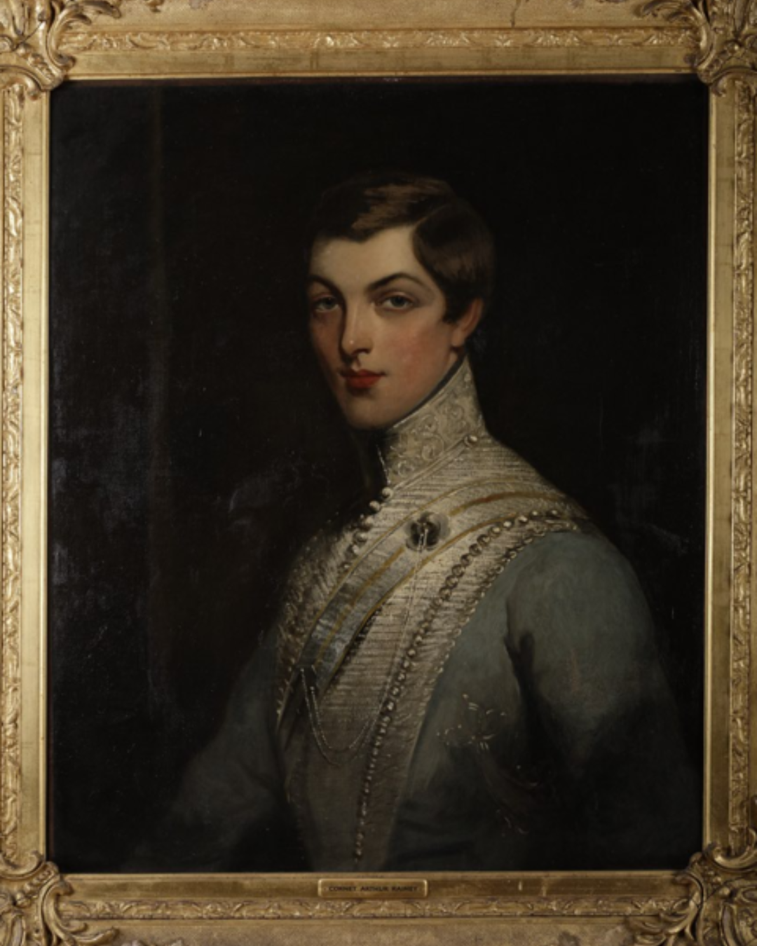 Portrait of a young woman in a military uniform, framed in an ornate gold frame.