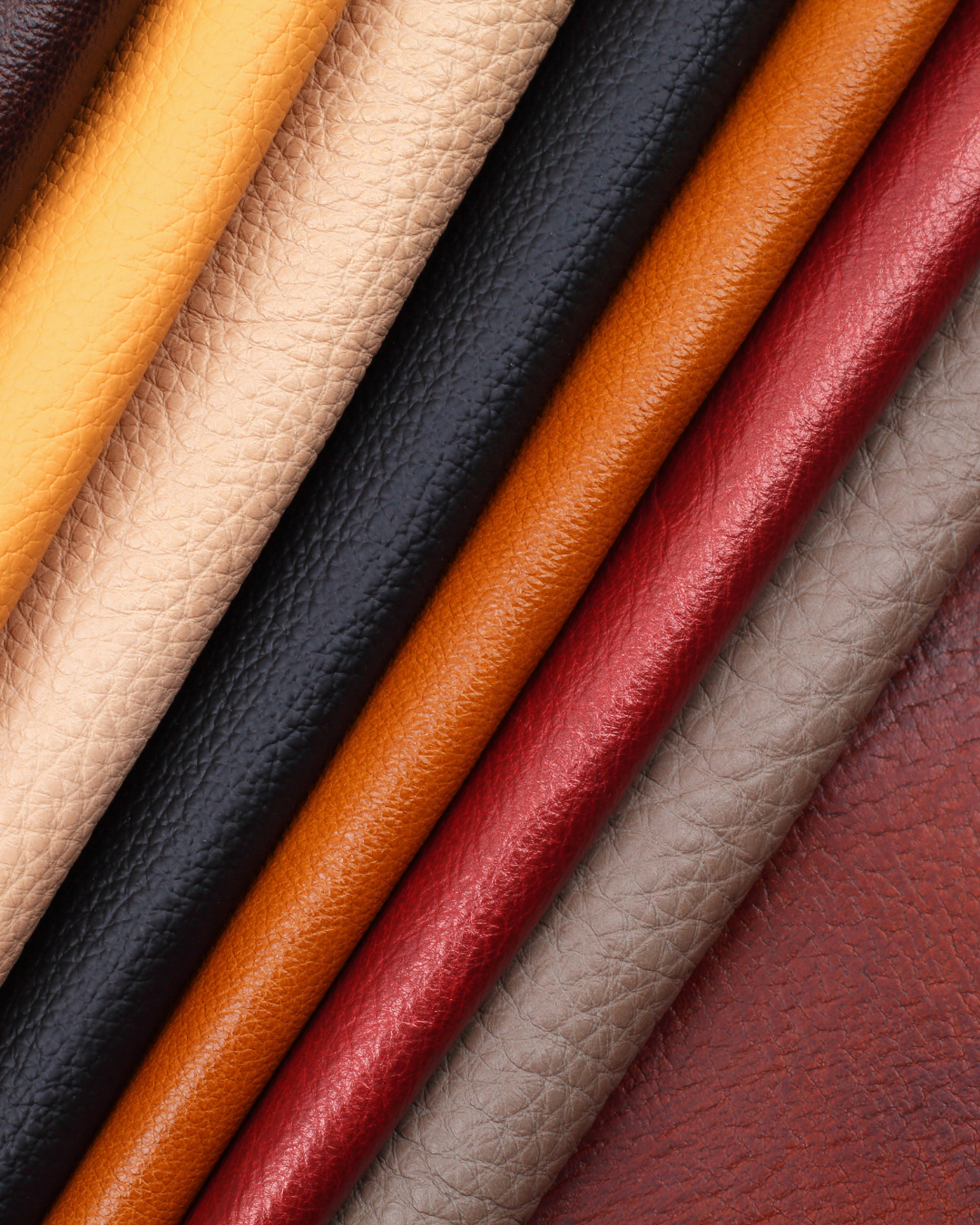 A close-up image of several rolled pieces of leather in various colors including yellow, beige, black, orange, red, and brown.