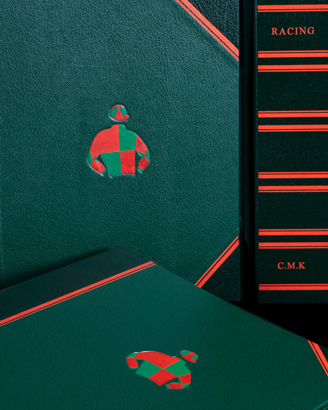 Green textured surface with a poker chip sticker of a jockey in red and green, and a black book with red lines and the word 'RACING' on the spine.