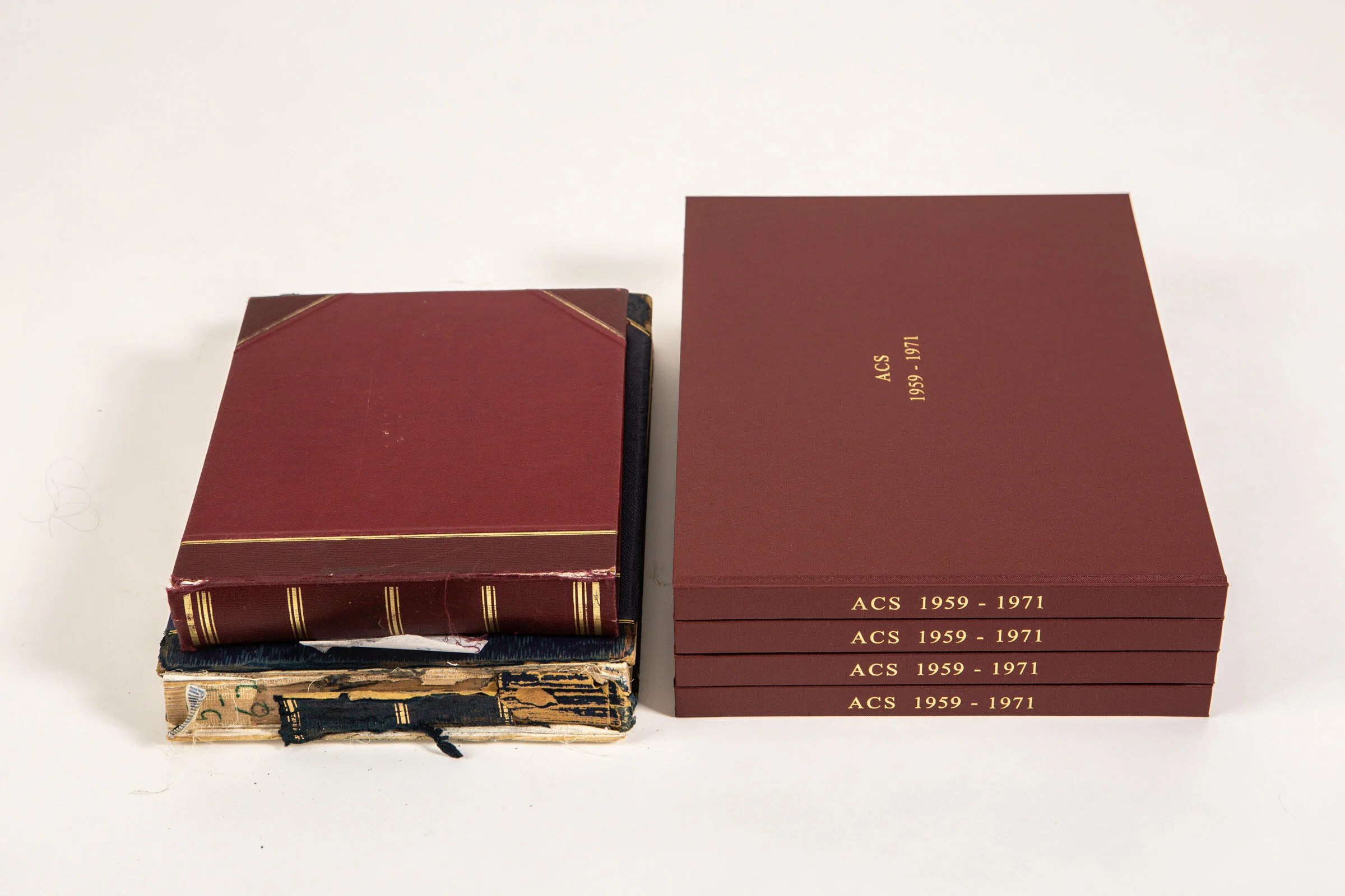 Three stacked vintage books next to a set of four maroon hardcover books with gold text on their spines and cover, titled "ACS 1959-1971."