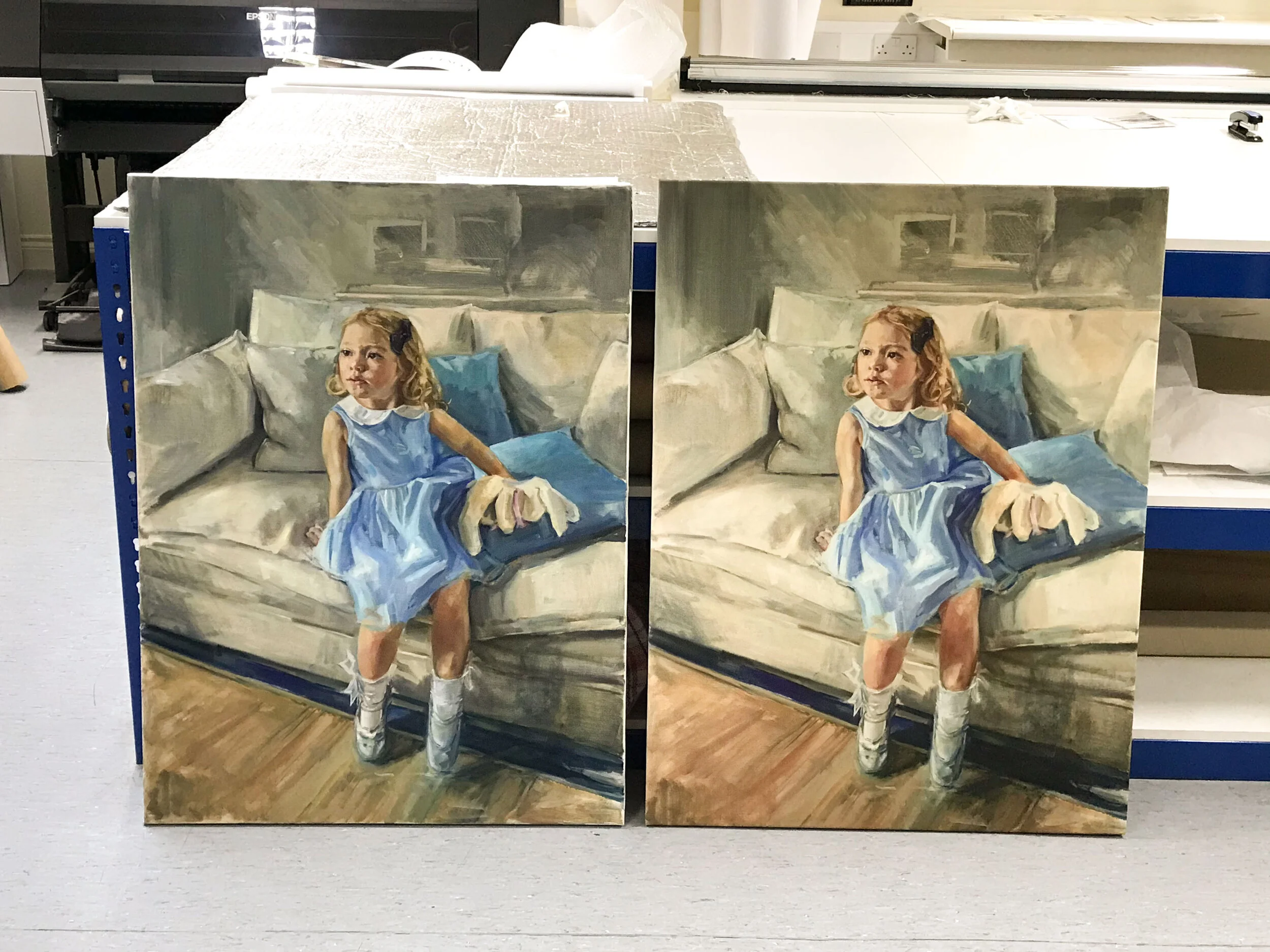 Two identical paintings of a young girl in a blue dress sitting on a sofa, with a light-colored background.