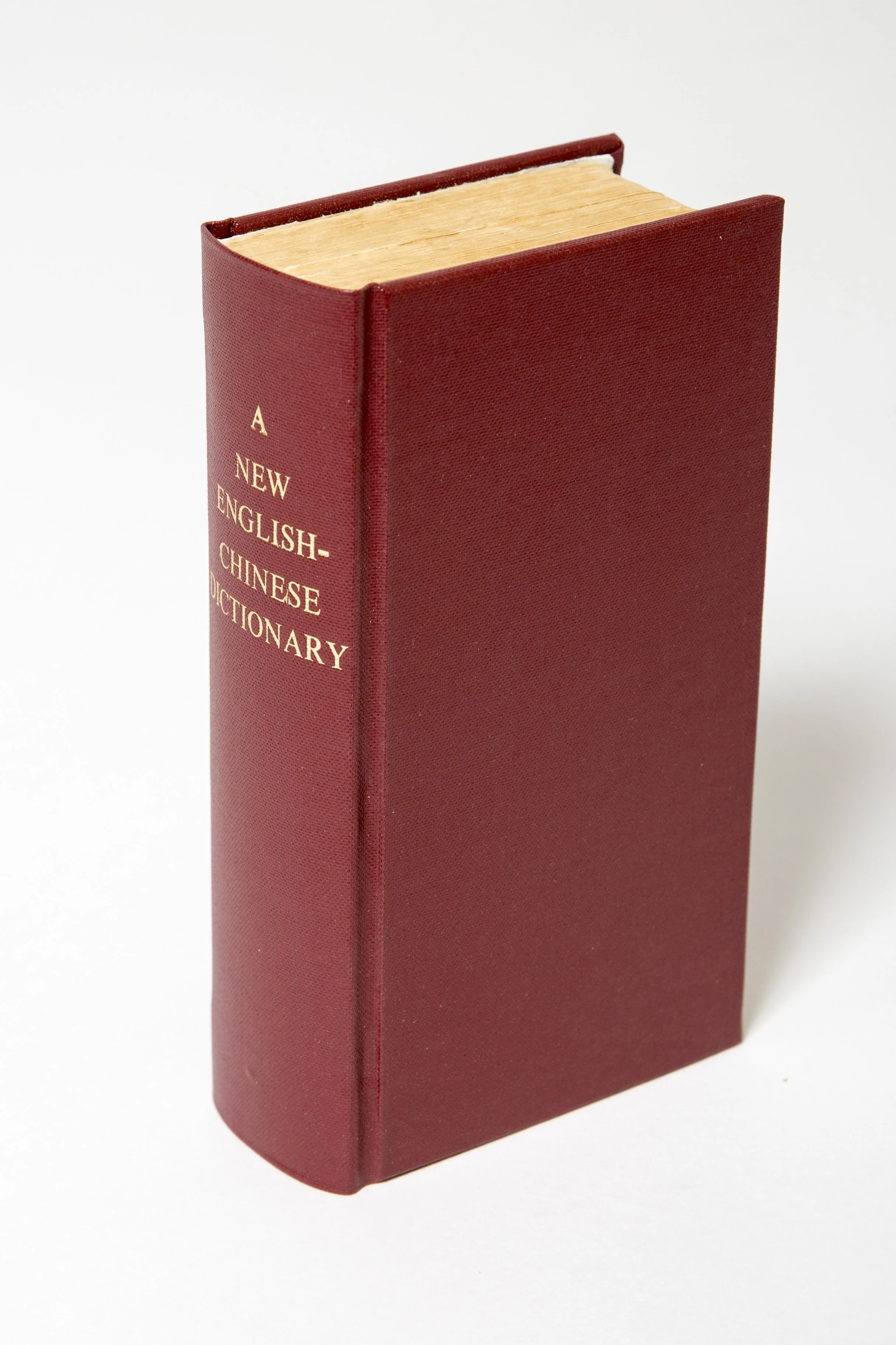 Red hardcover book titled 'A New English-Chinese Dictionary' standing upright against a white background.