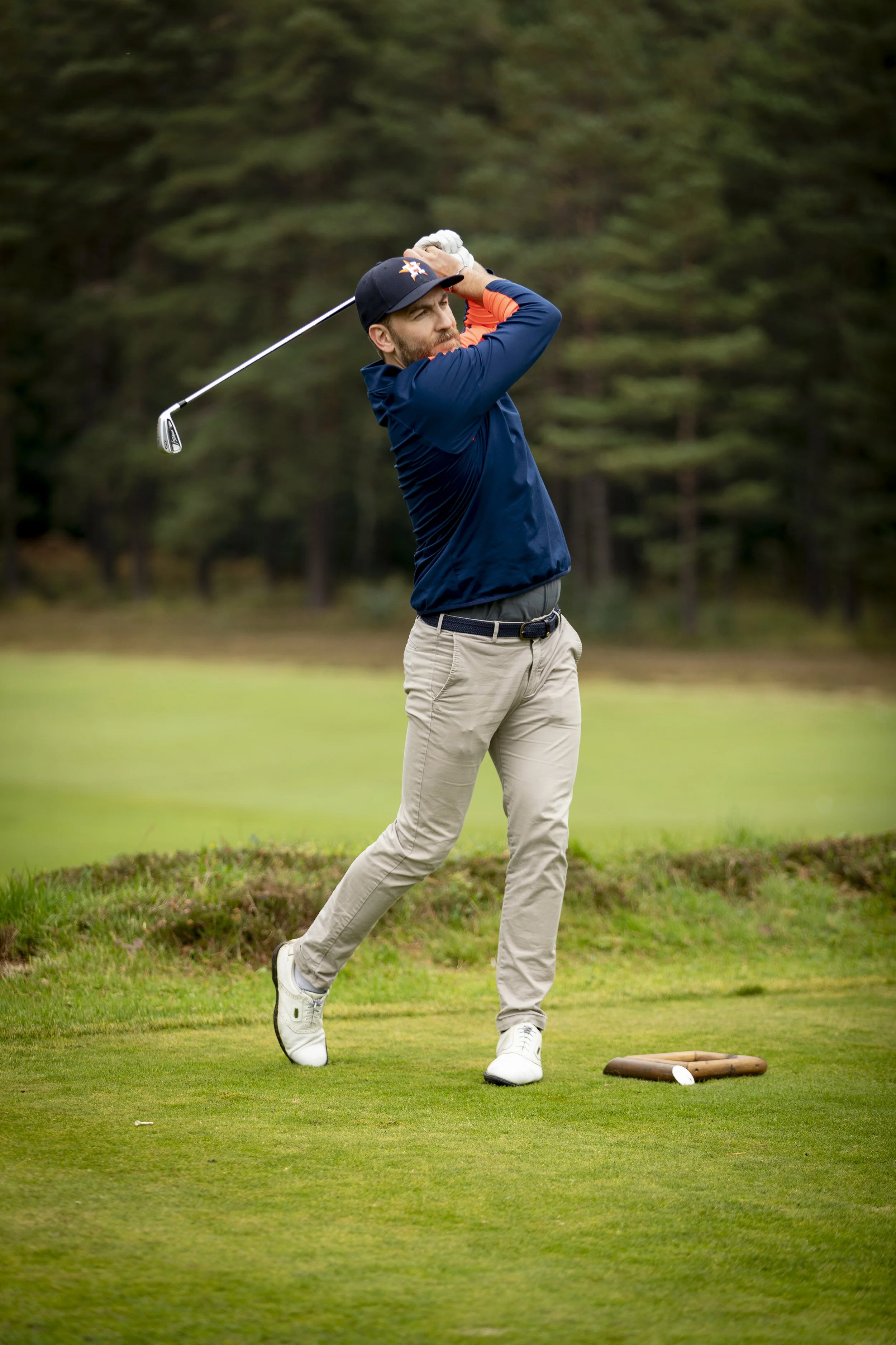 A man playing golf on a lush green golf course, swinging a golf club.