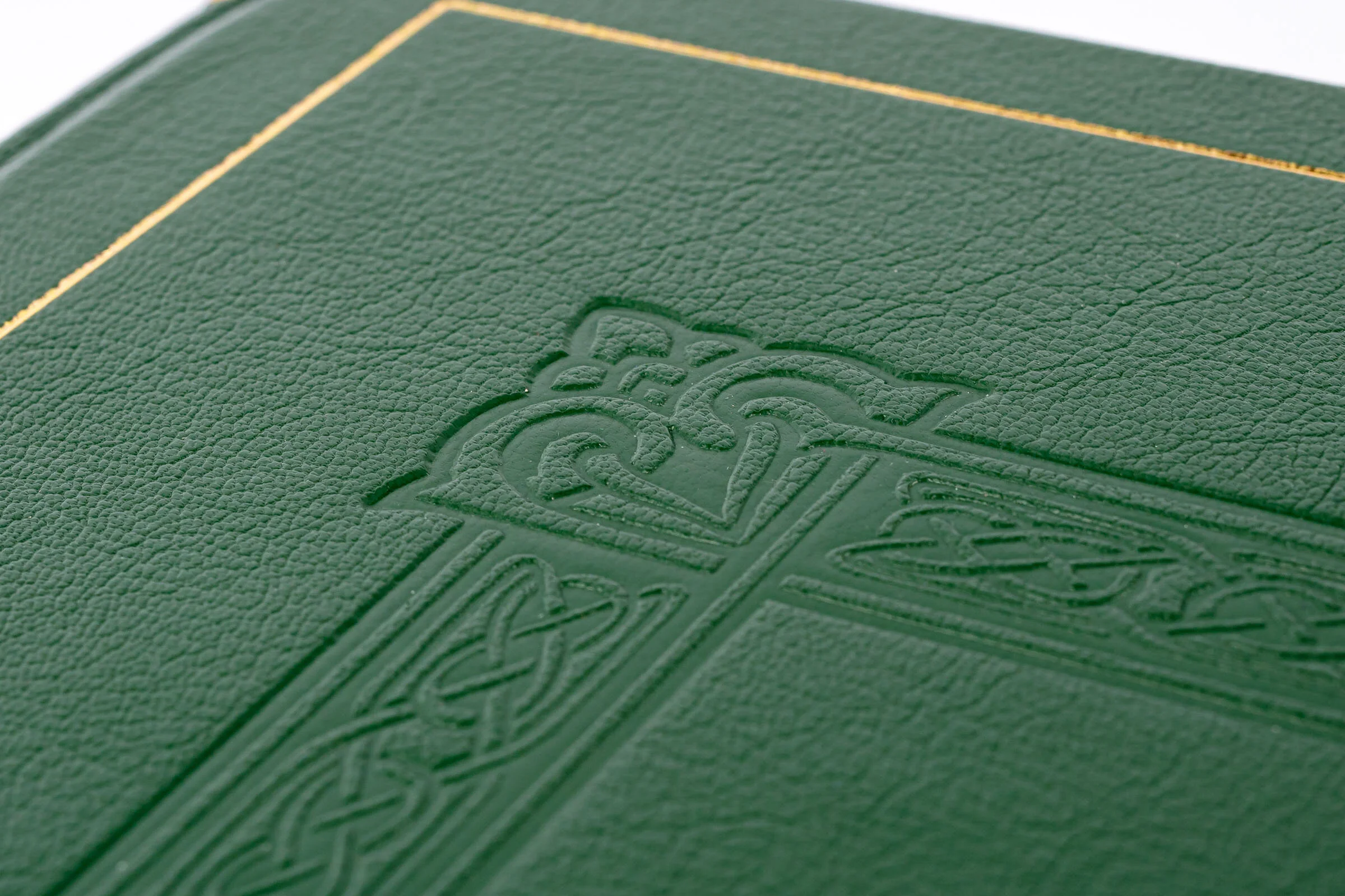 Close-up of a green textured cover with an embossed design featuring a crown and intricate patterns.