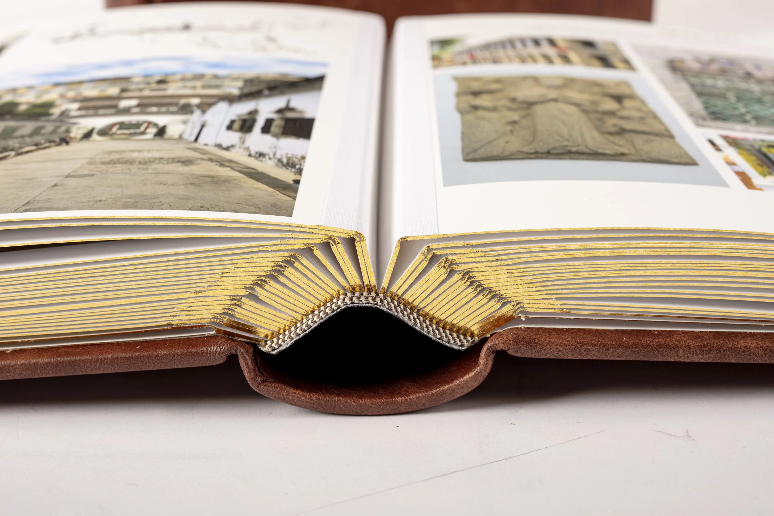 Open photo album showing photographs of buildings and artwork on a white surface.
