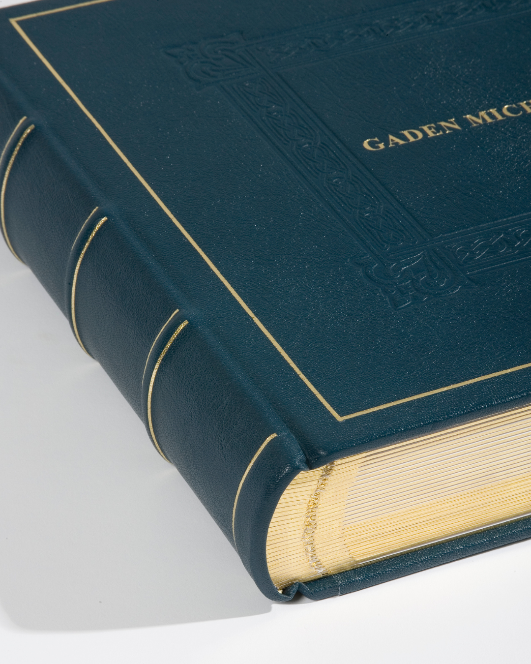 Close-up of a large, dark blue, leather-bound book with gold embossed detailing and the title 'GADEN MICHI' on the cover.