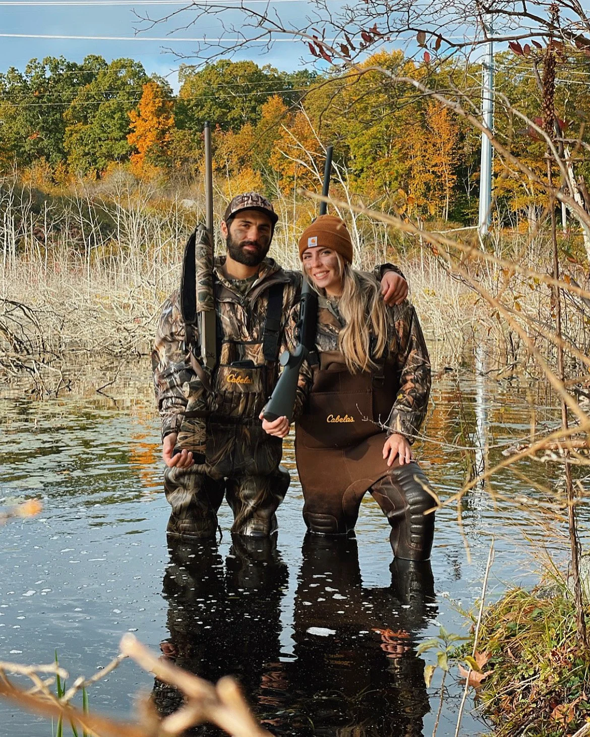 couple standing in water with hunting gear