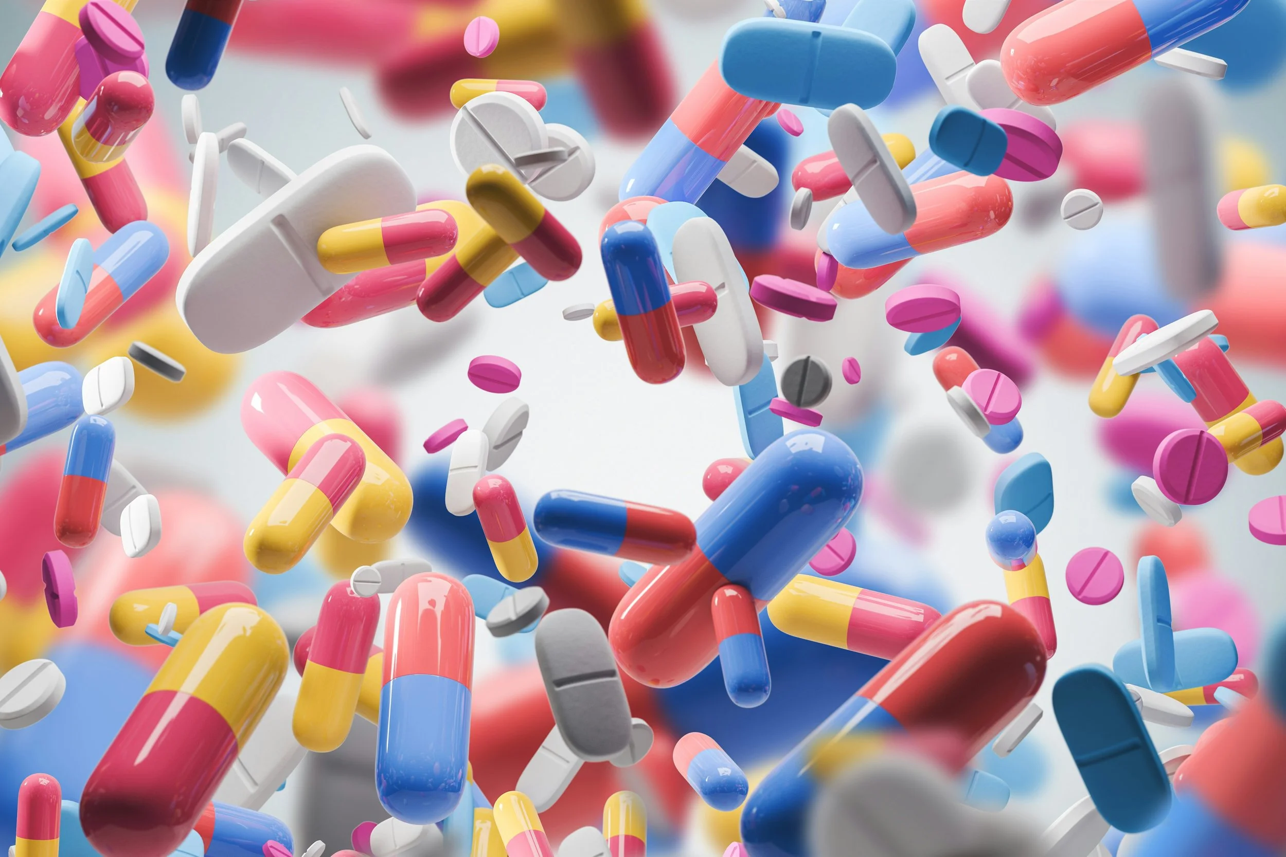 Numerous colorful capsules and tablets floating in a cloud-like formation.