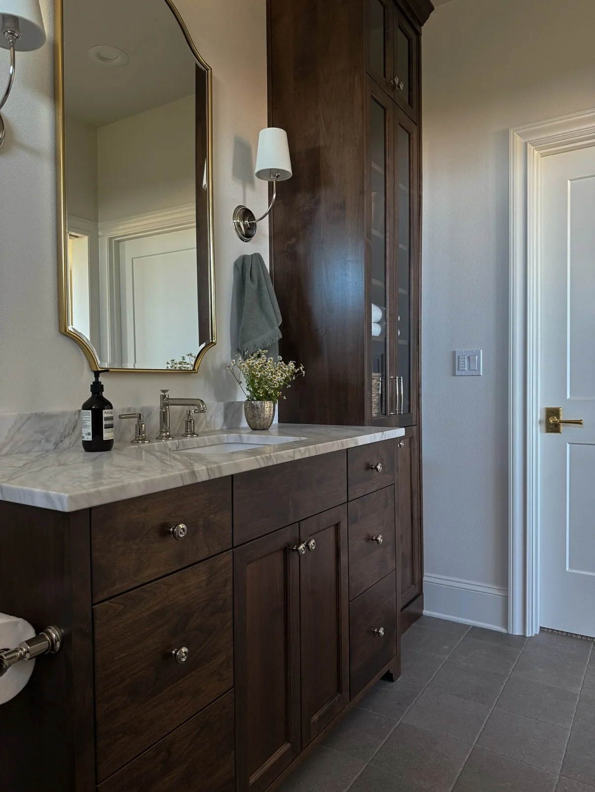 This stunning en-suite is a masterclass in mixing classic finishes. Calcutta gold marble meets warm polished nickel fixtures, while thoughtful tile patterns combine dark sage gloss with white zellige. The result is a space that's both timeless and ca